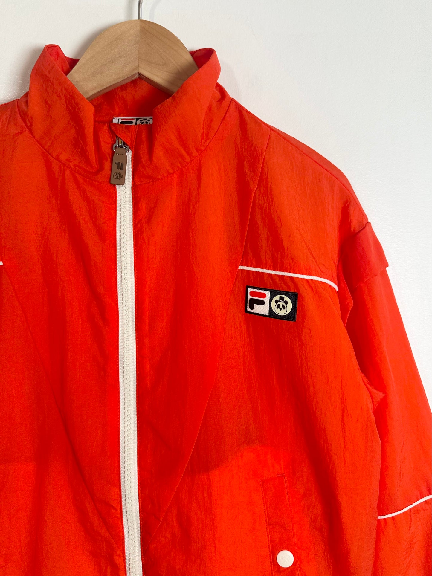 Orange jacket with a brand logo on a hanger against a white background