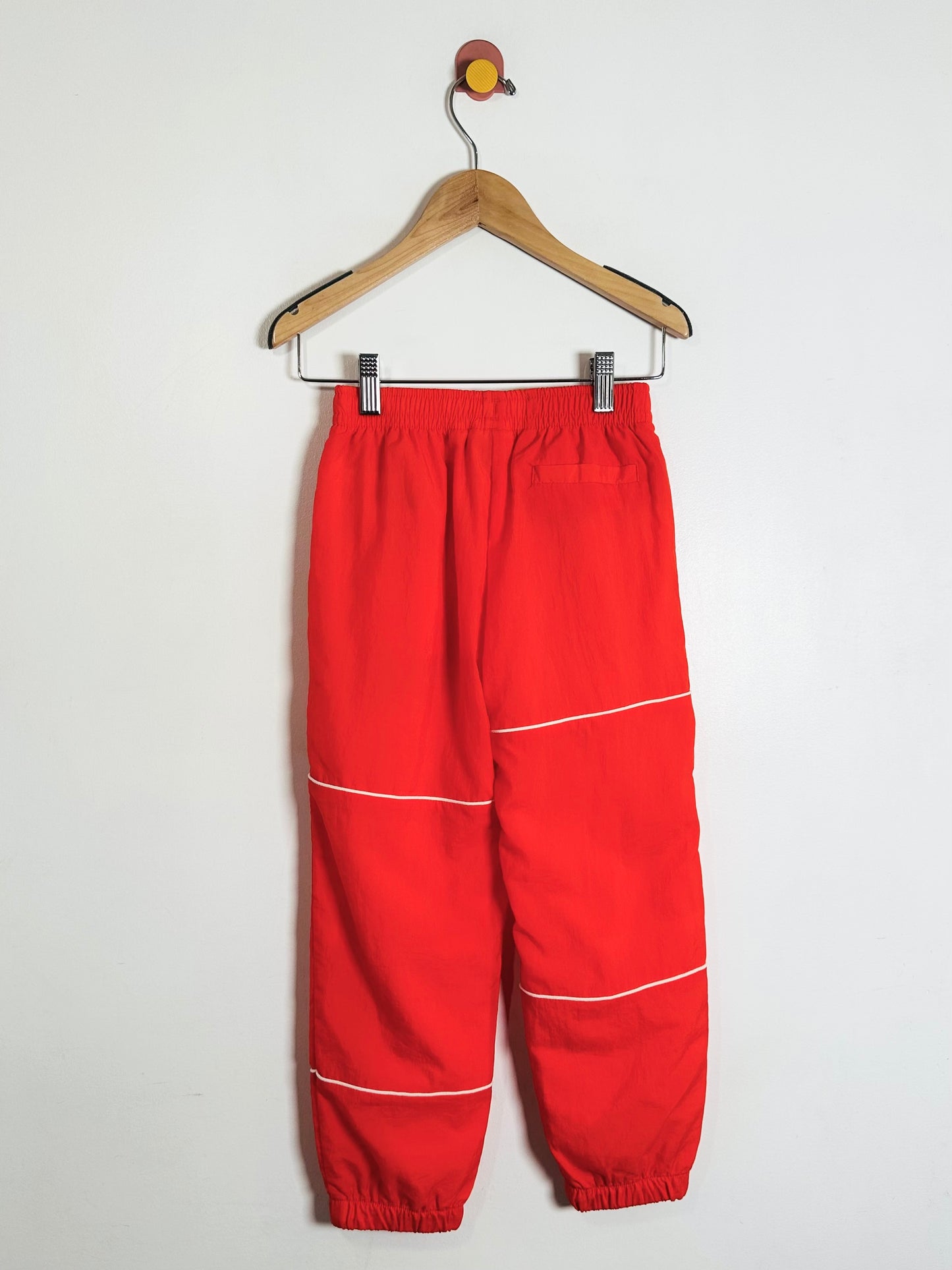 Red pants with white stripes on a hanger against a white background