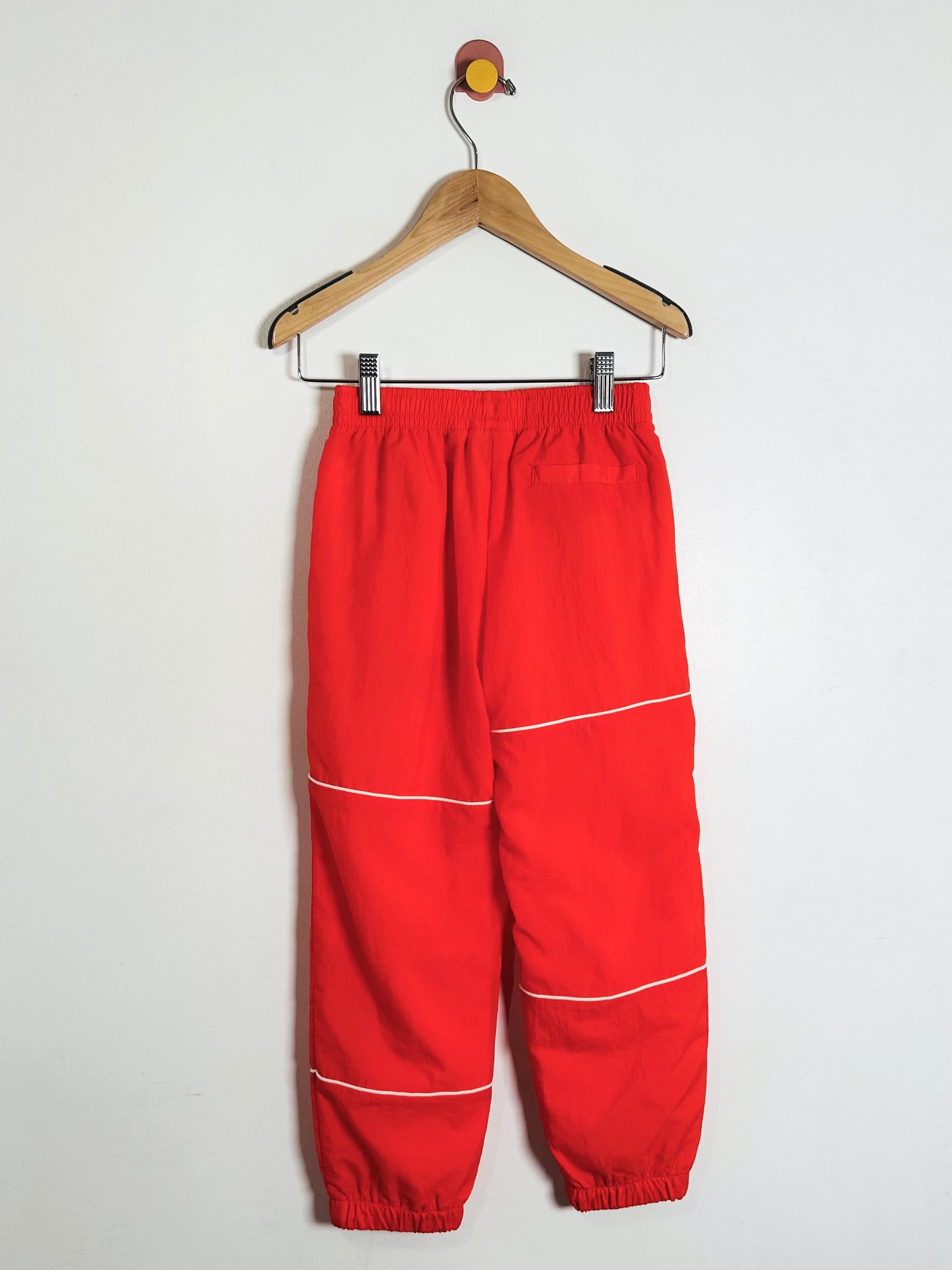 Red pants with white stripes on a hanger against a white background