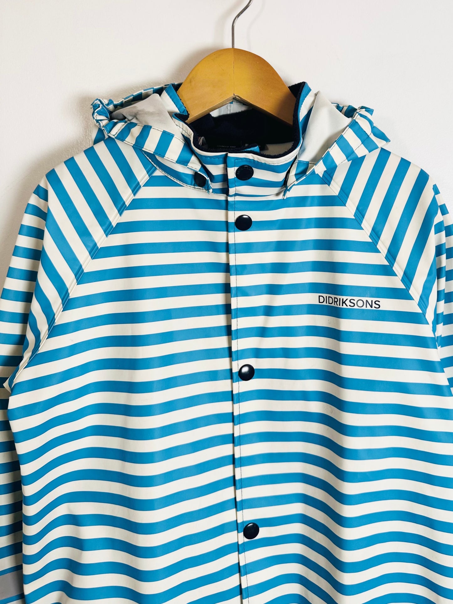 Blue and white striped jacket with 'Didriksons' branding on a wooden hanger against a white background.