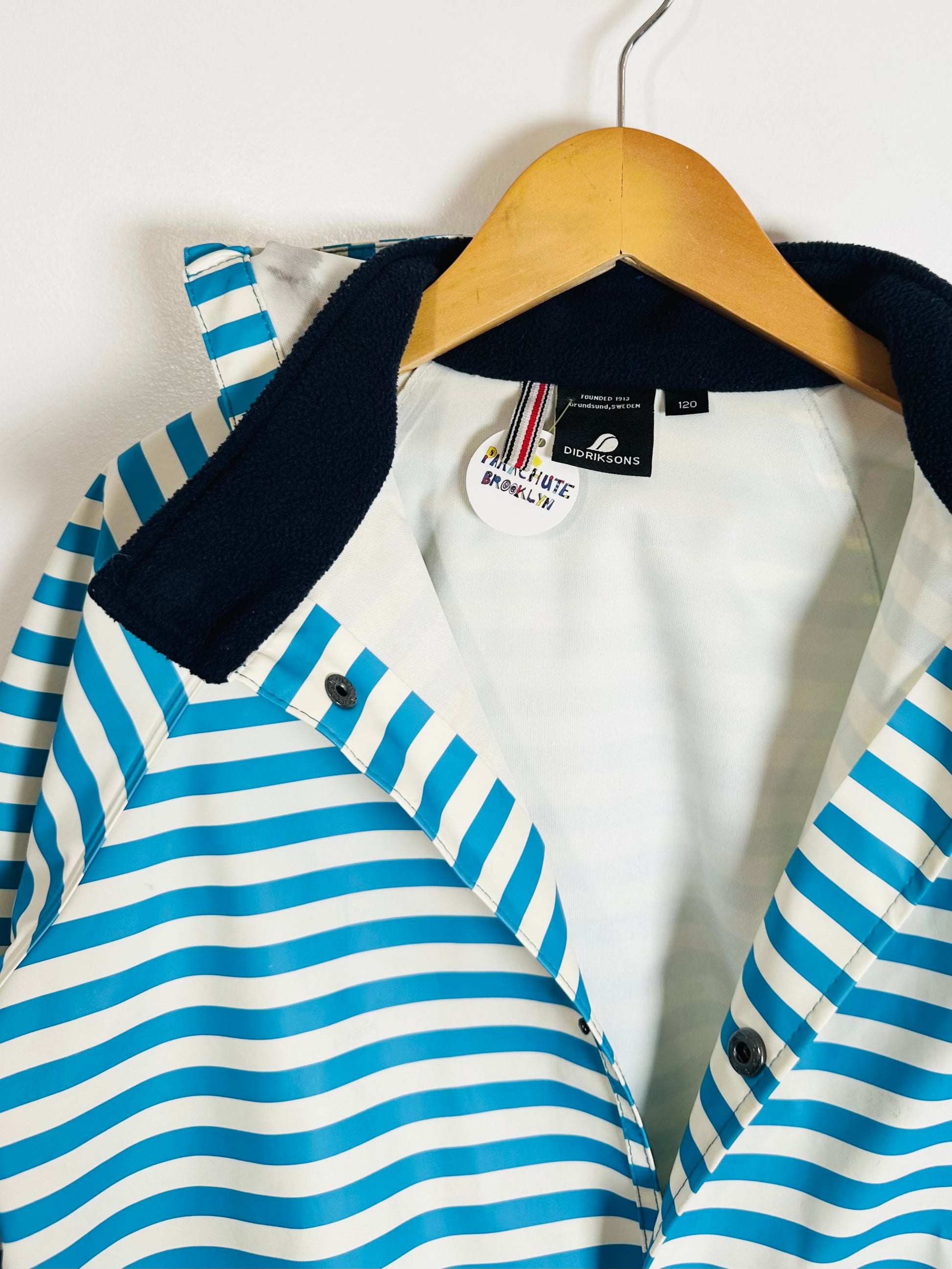 Blue and white striped jacket with black collar on a hanger against a white background