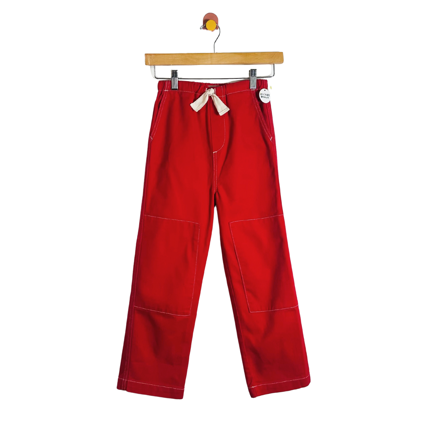 Red pants hanging on a wooden hanger against a white background