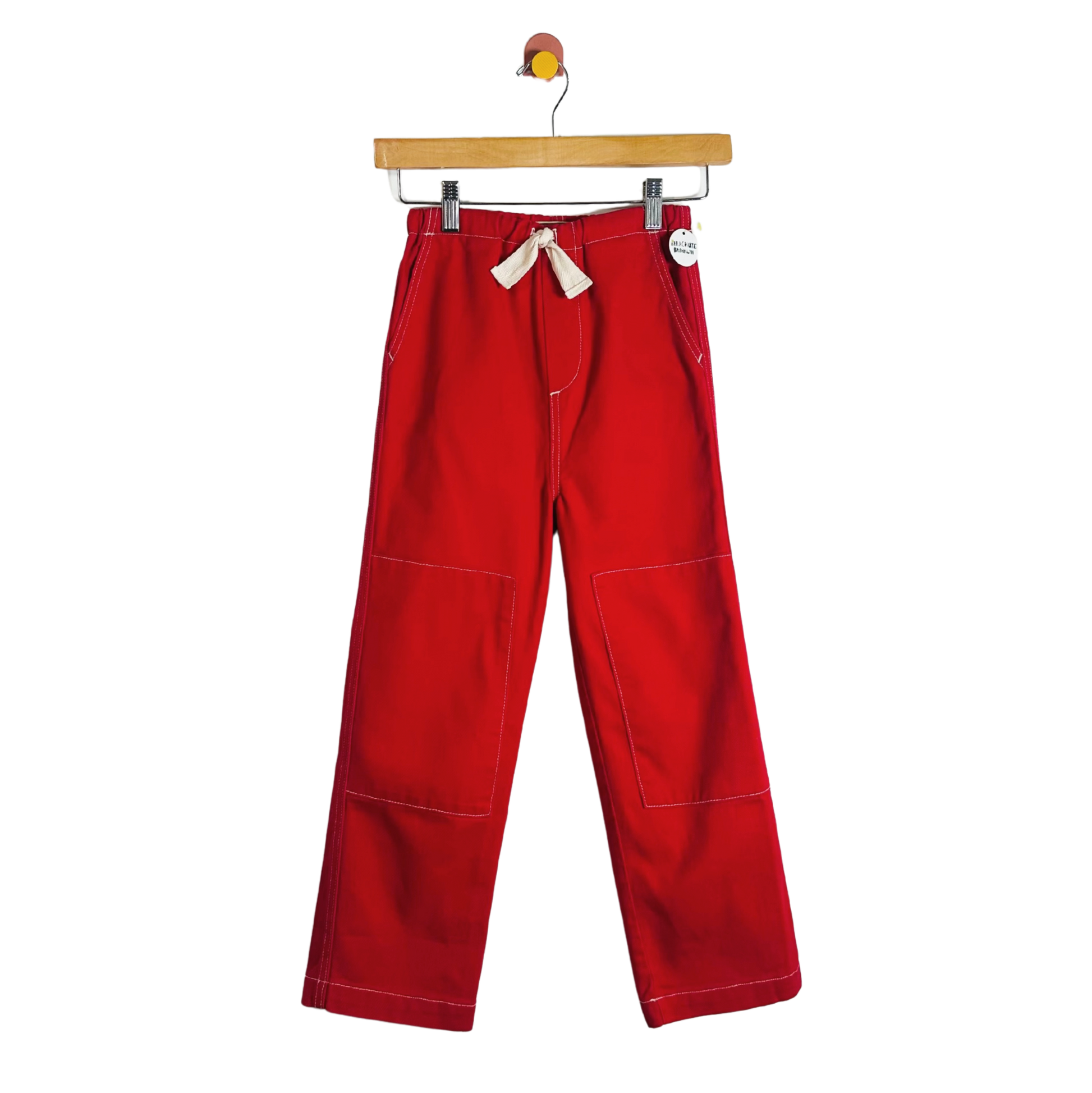 Red pants hanging on a wooden hanger against a white background