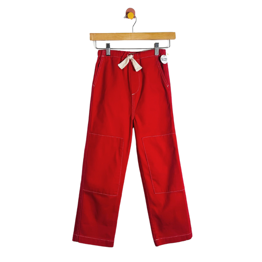 Red pants hanging on a wooden hanger against a white background