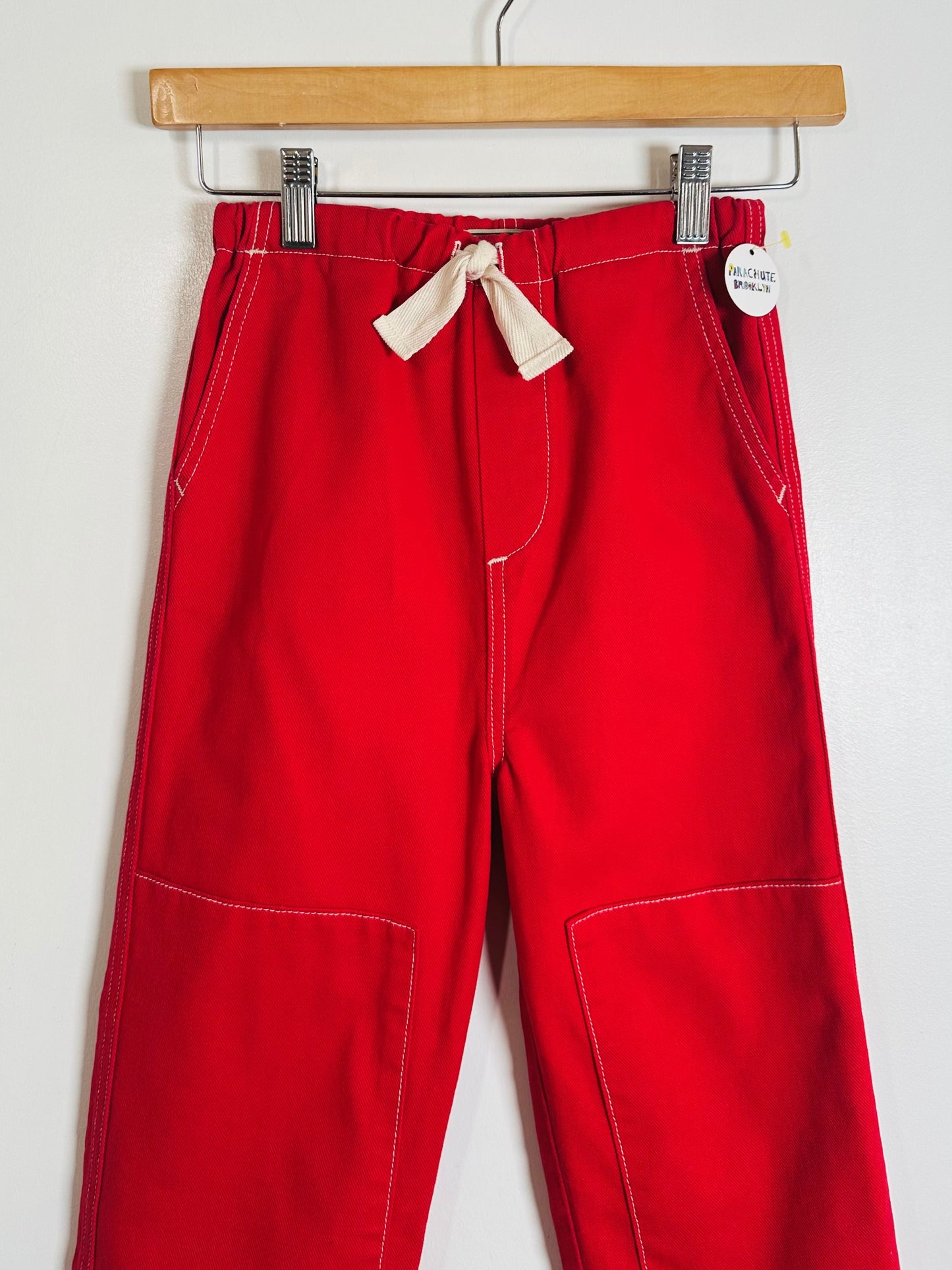 Red pants with a drawstring on a hanger against a white background