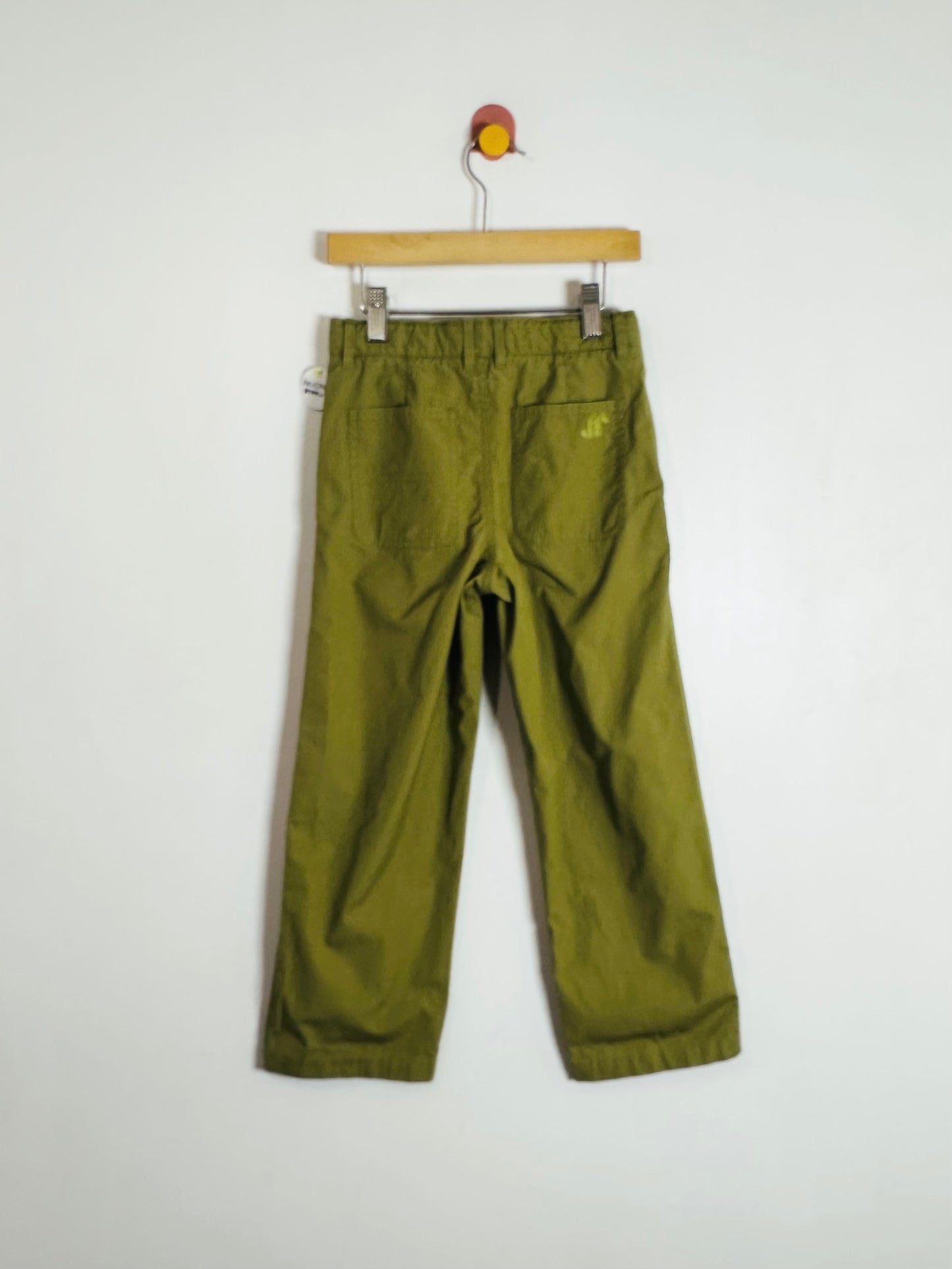 Green pants on a wooden hanger against a white background