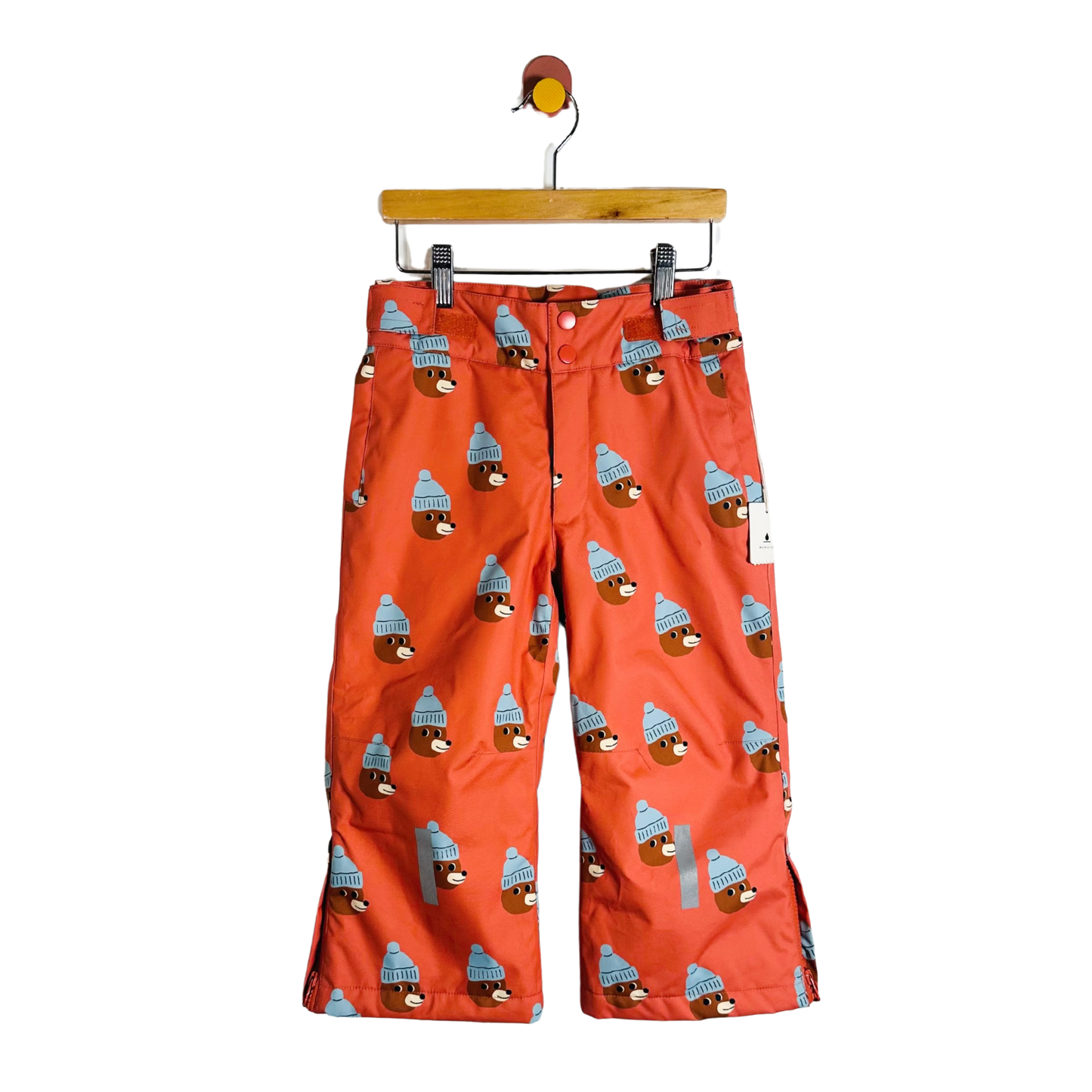 Red pants with bear pattern on a hanger against a white background
