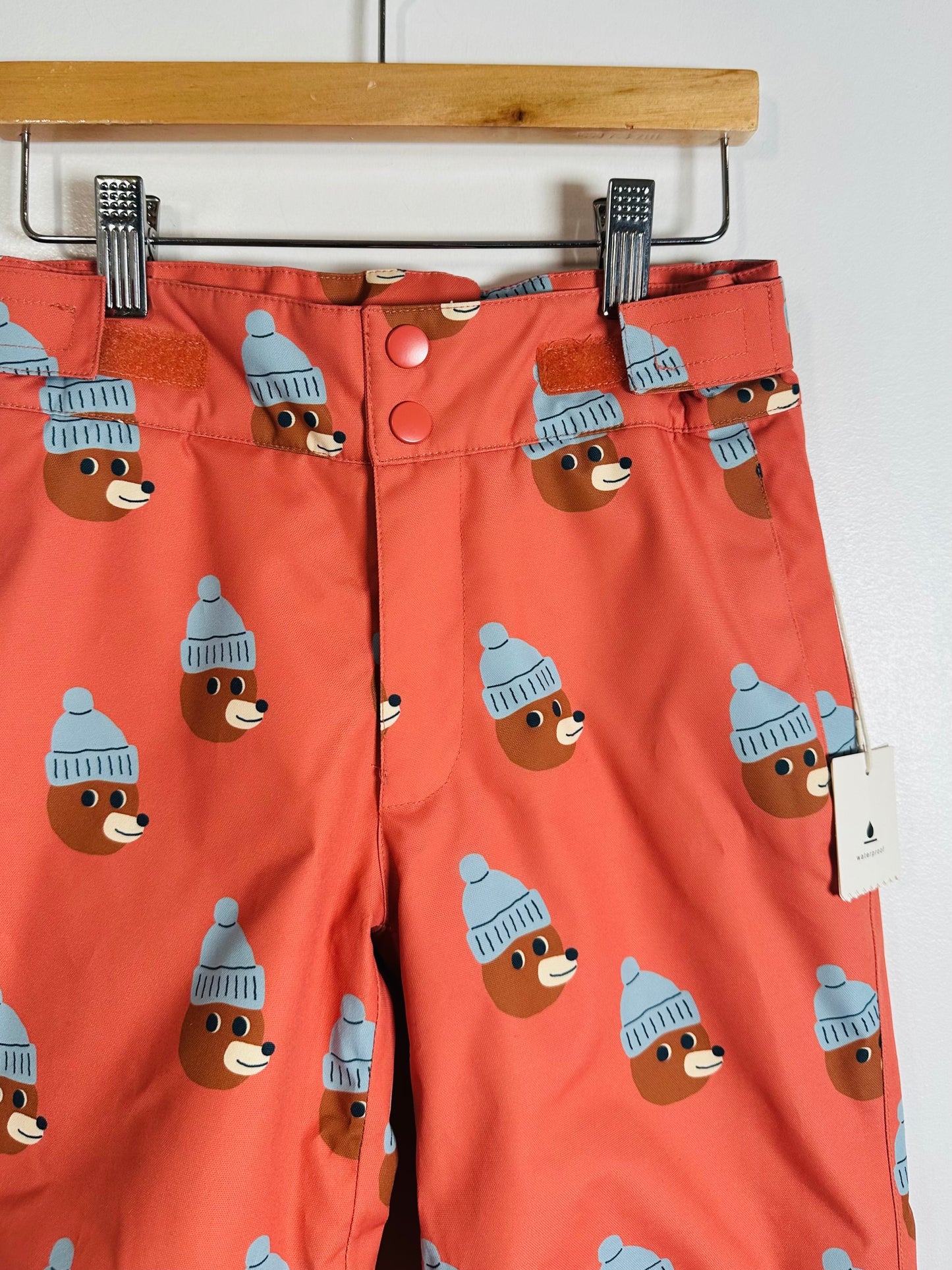 Pants with bear pattern wearing hats on a hanger against a white background