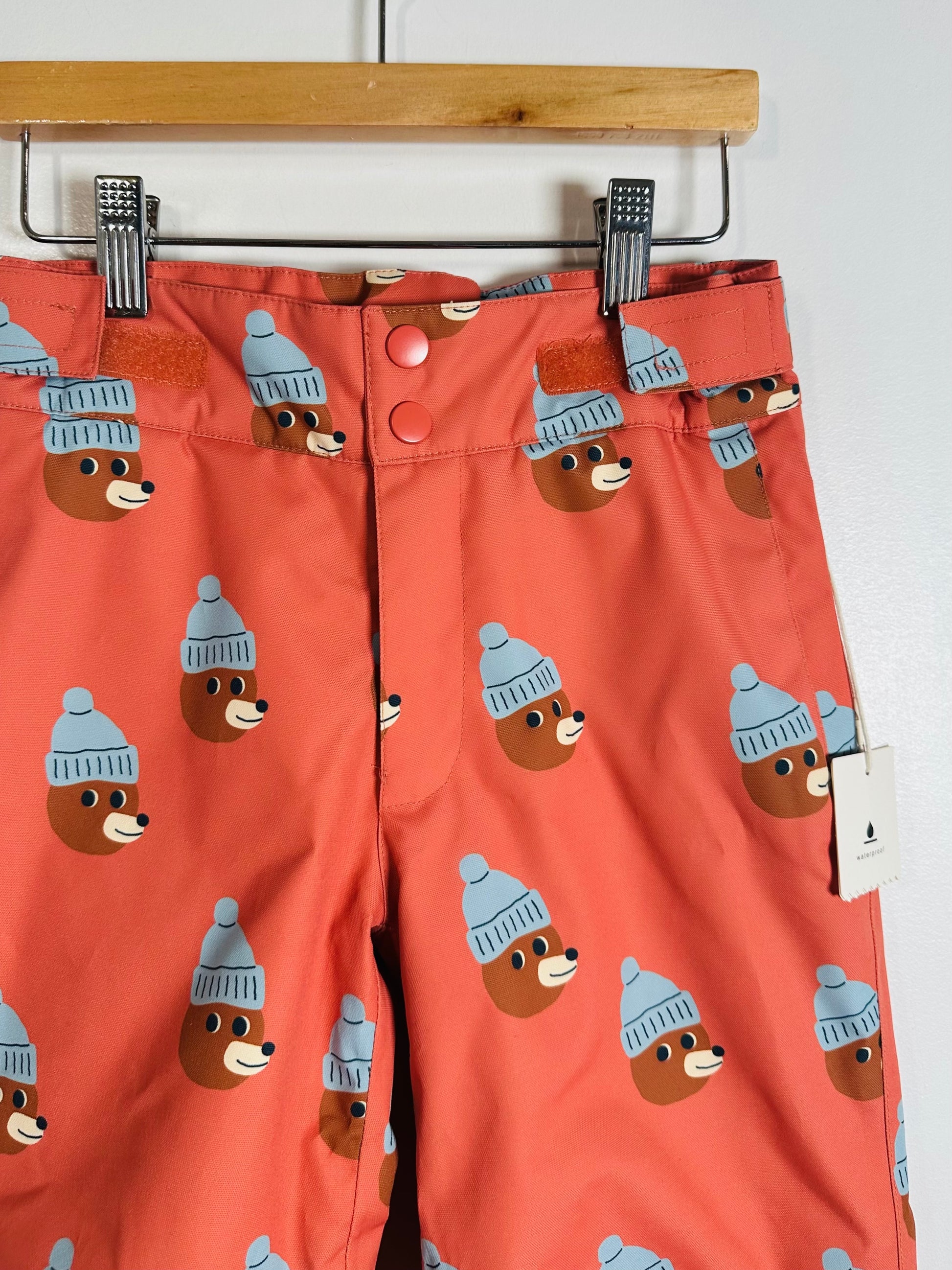 Pants with bear pattern wearing hats on a hanger against a white background