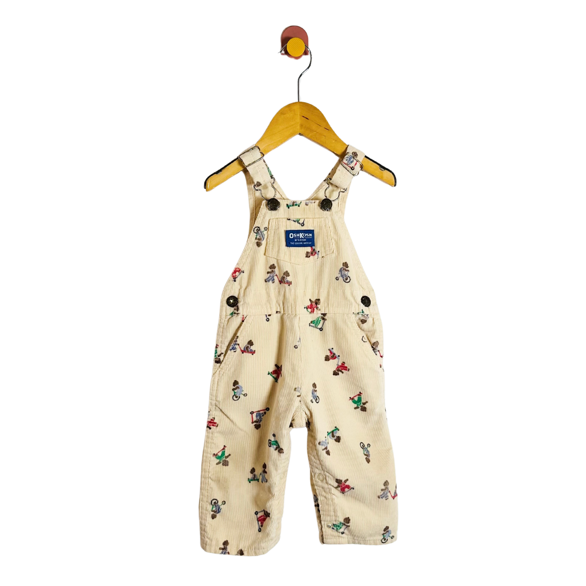 Beige children's overalls with colorful patterns on a hanger against a white background