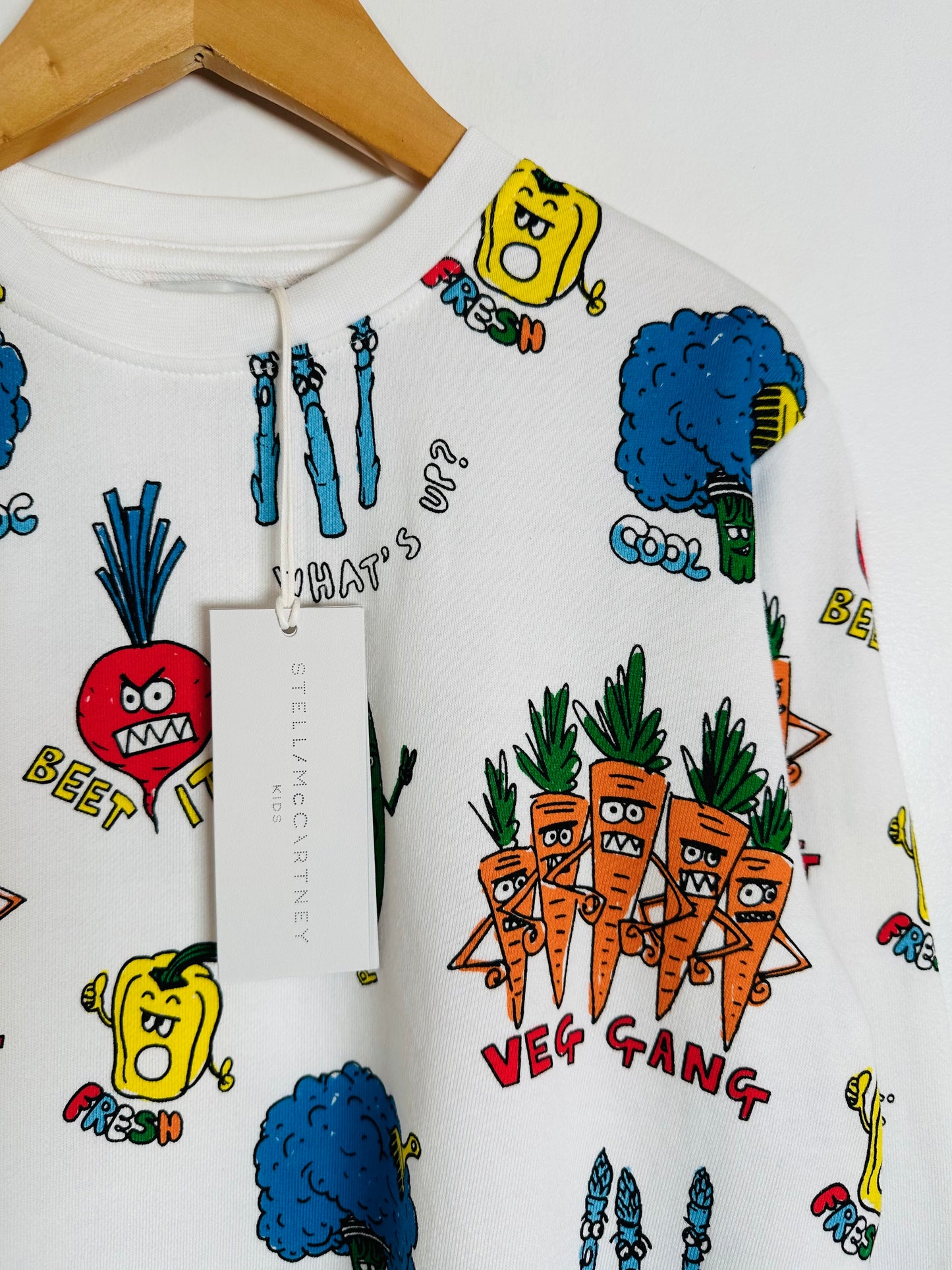 White sweatshirt with colorful vegetable-themed designs and Stella McCartney tag.