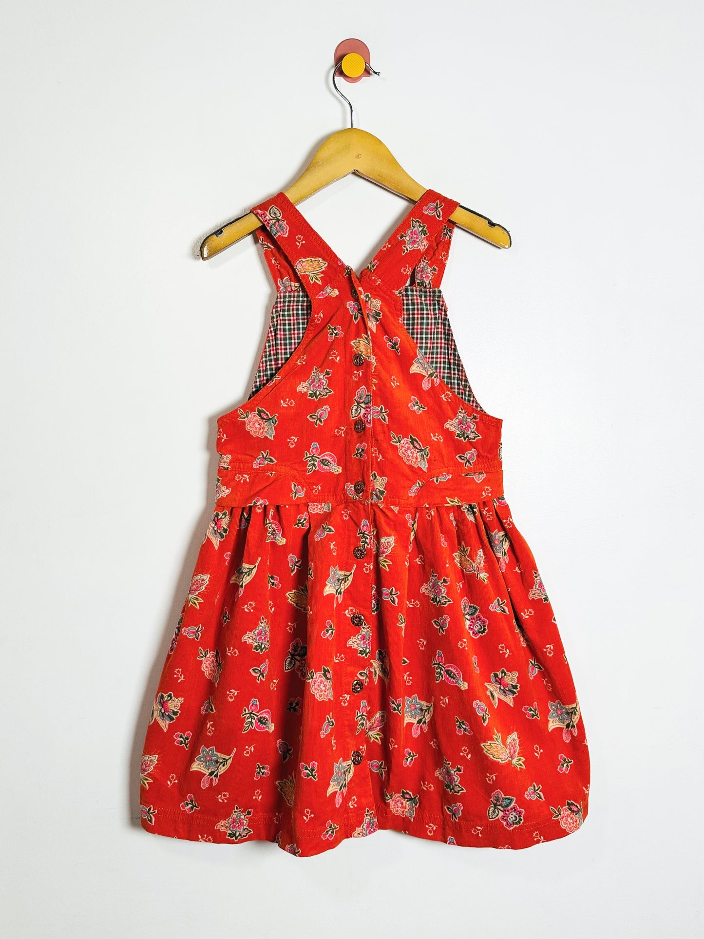 Red dress with floral pattern on a hanger against a white background