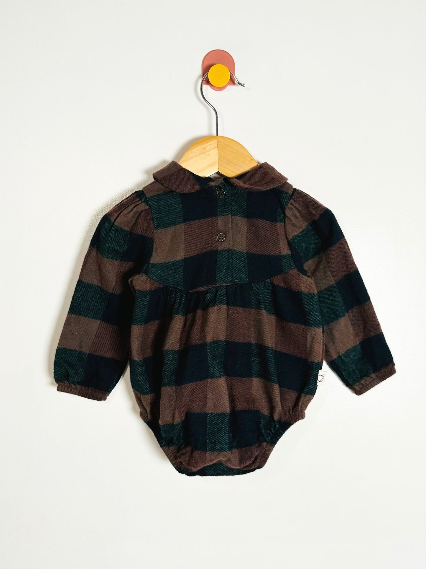 Plaid baby romper on a hanger against a white background