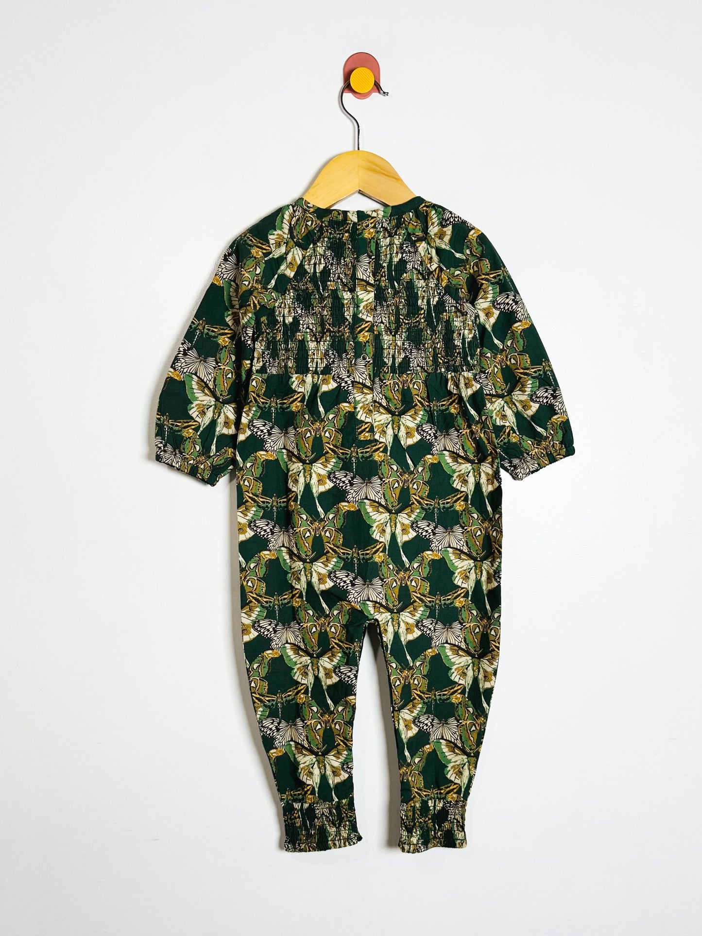 Green patterned onesie on a hanger against a white background
