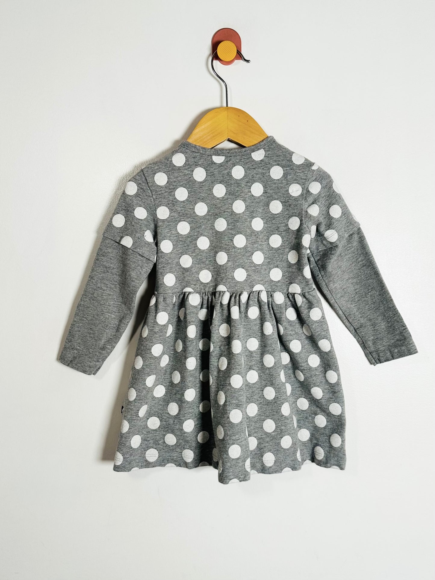 Gray dress with white polka dots on a hanger against a white background