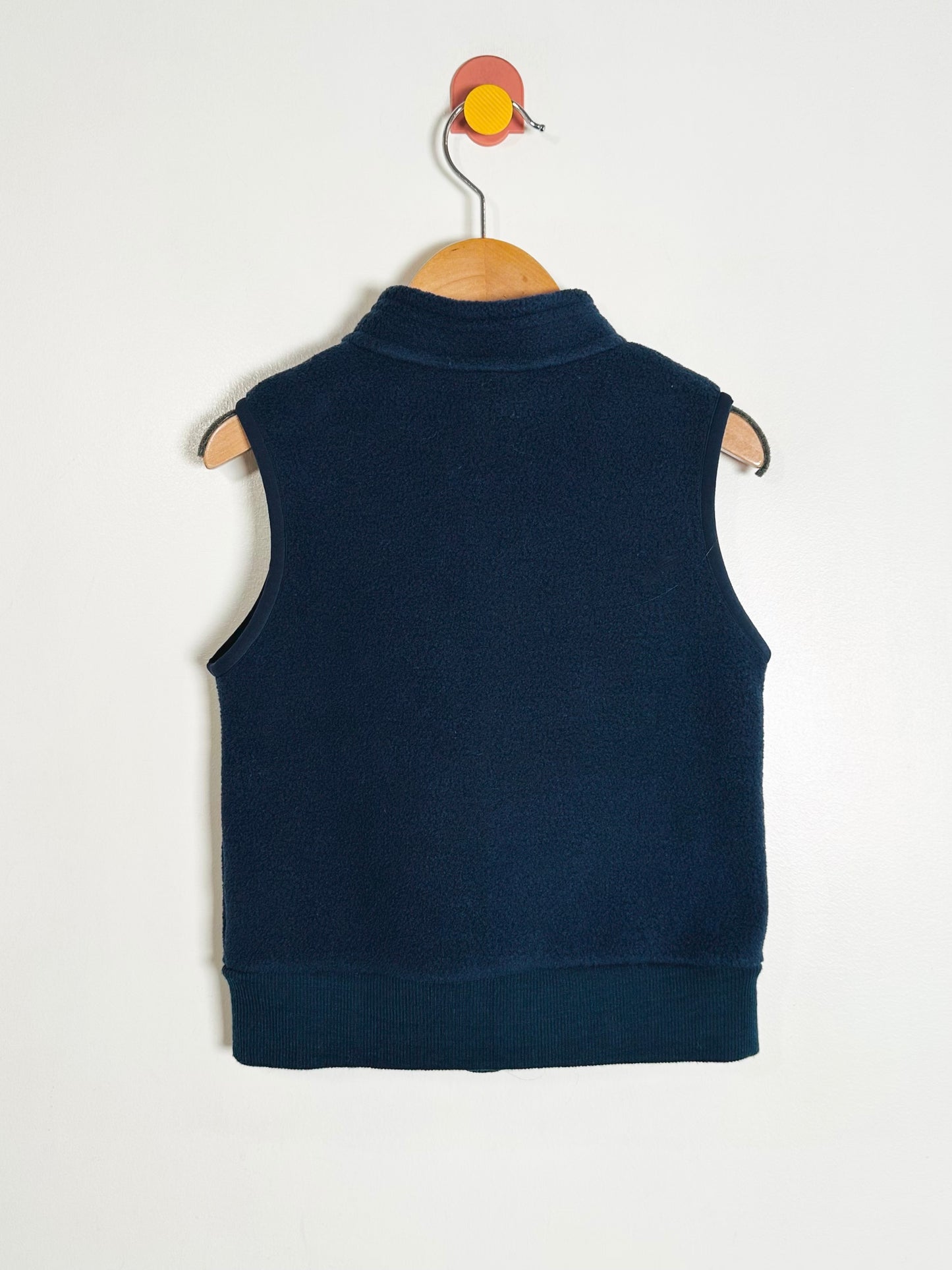Navy blue vest on a hanger against a white background
