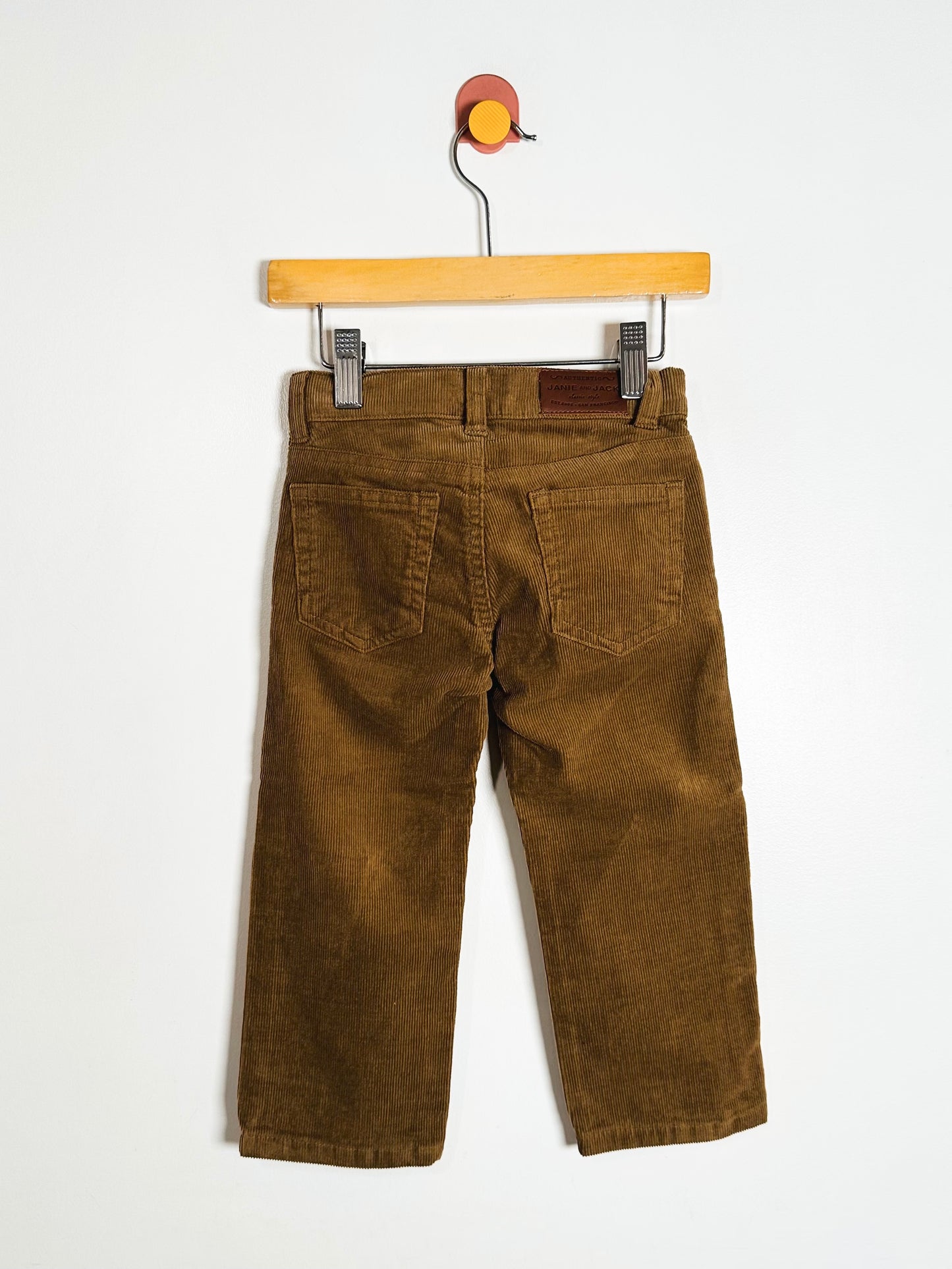 Brown pants on a wooden hanger against a white background