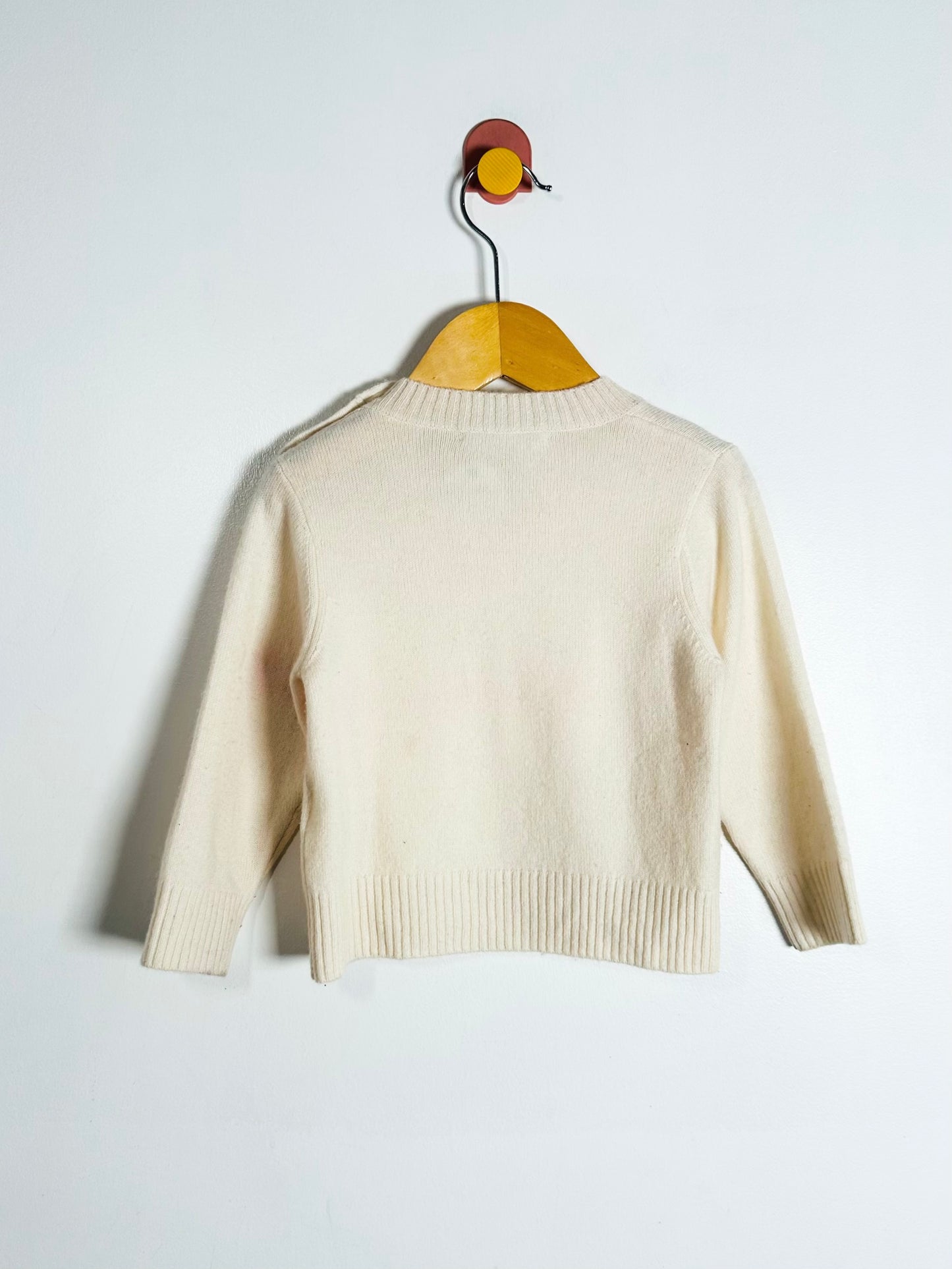 Beige sweater on a wooden hanger against a white background