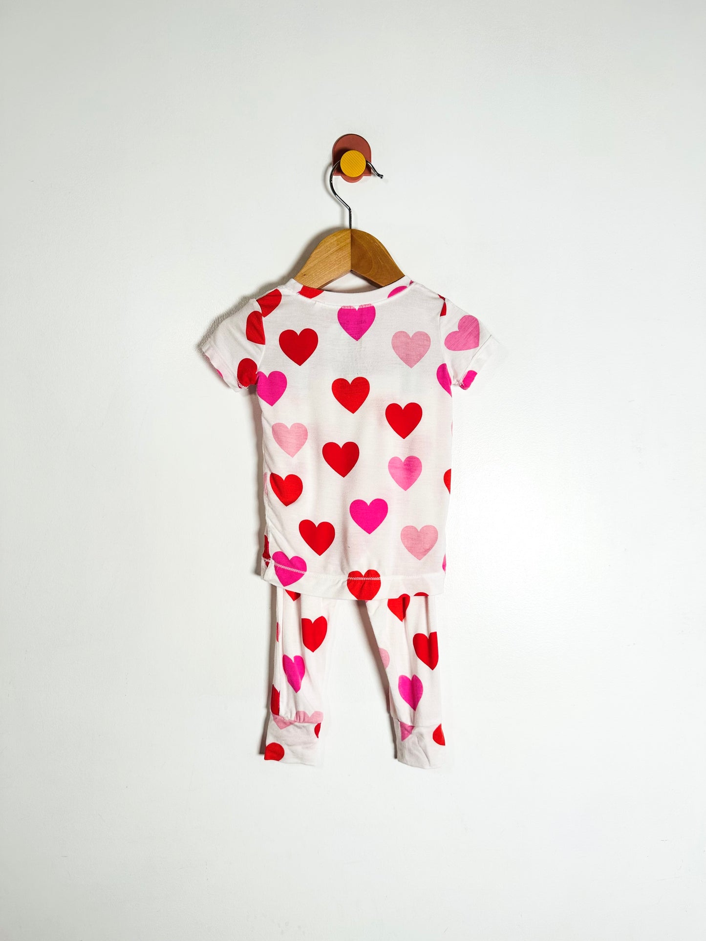 Children's outfit with heart pattern on a hanger against a white background