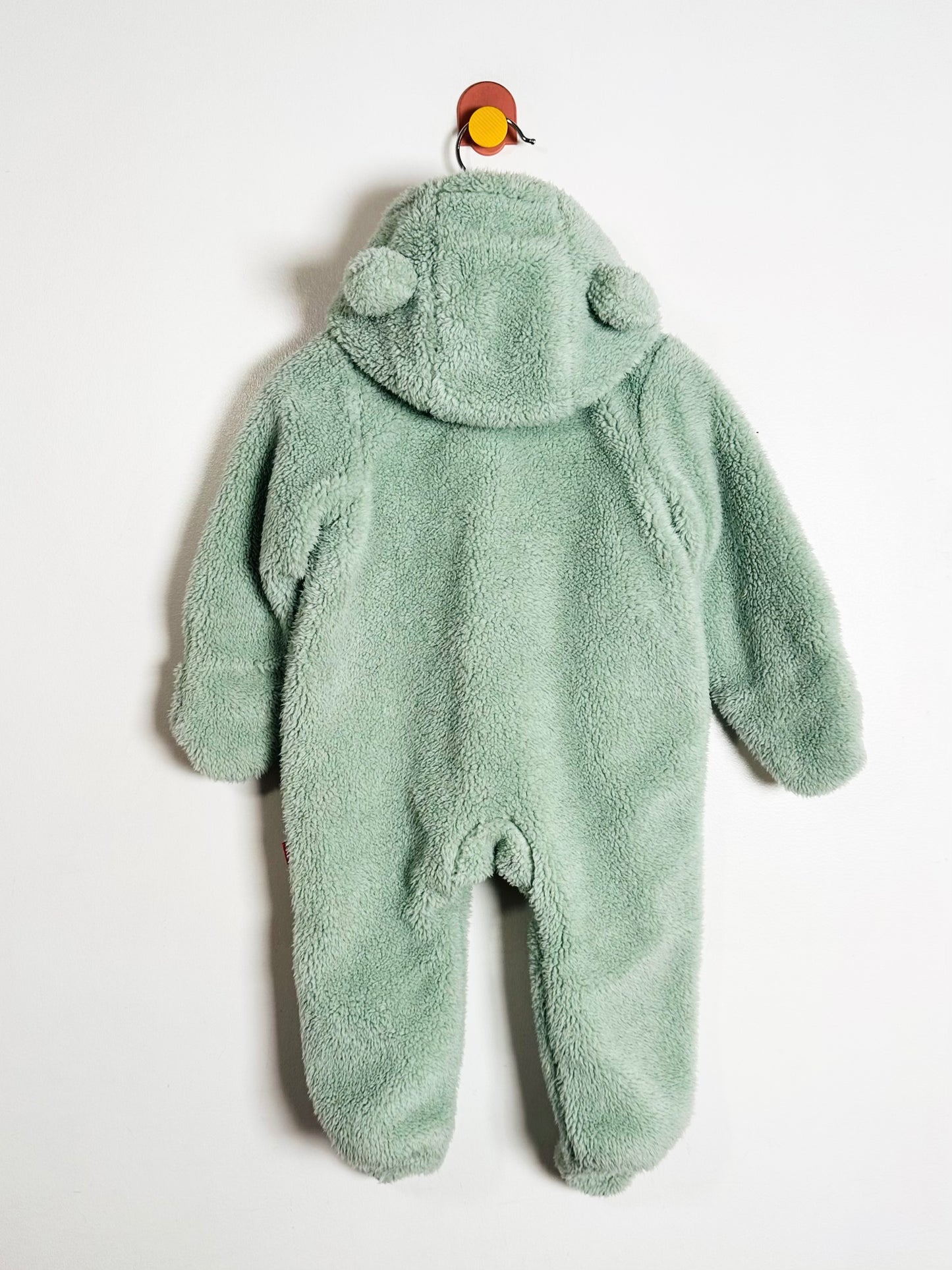 Green baby onesie with bear ears and a hood on a white background