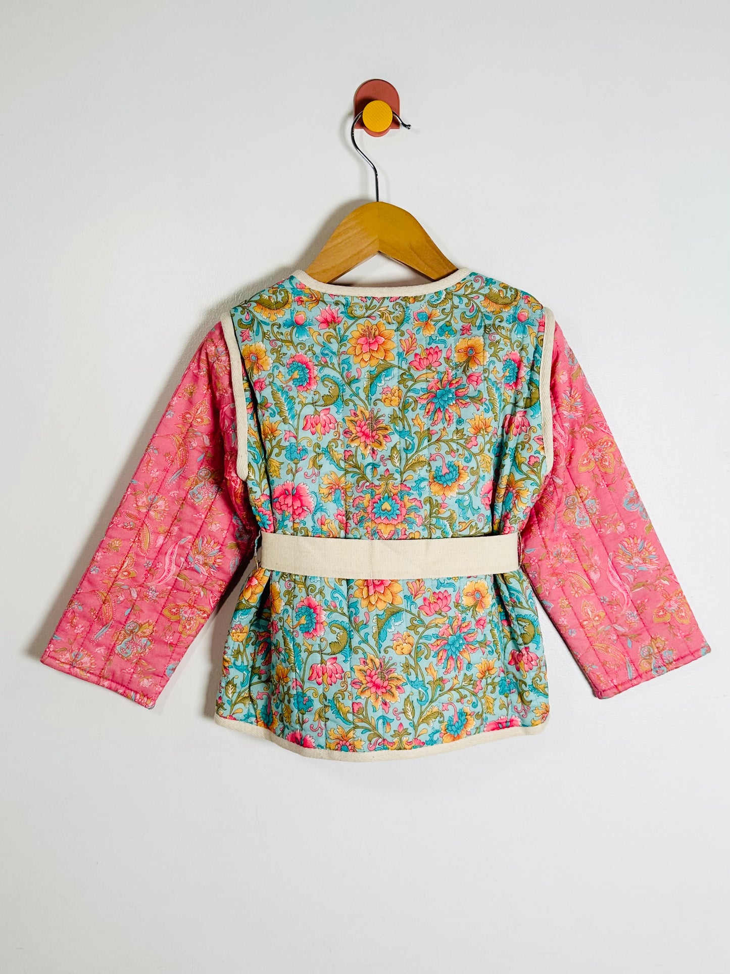 Children's floral jacket with pink sleeves on a hanger against a white background