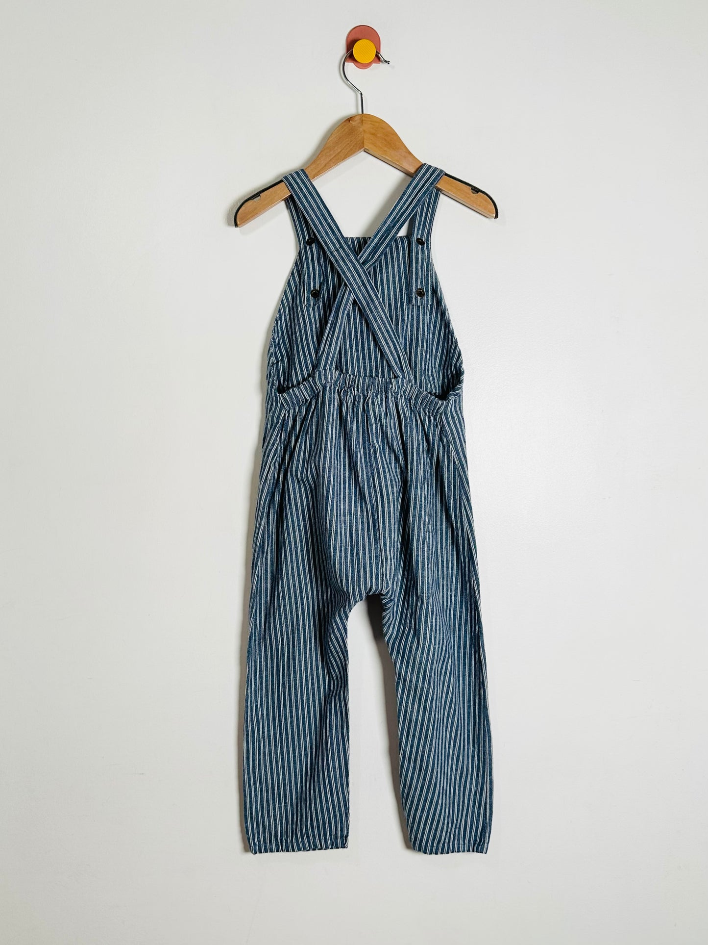 Blue striped overalls on a hanger against a white background