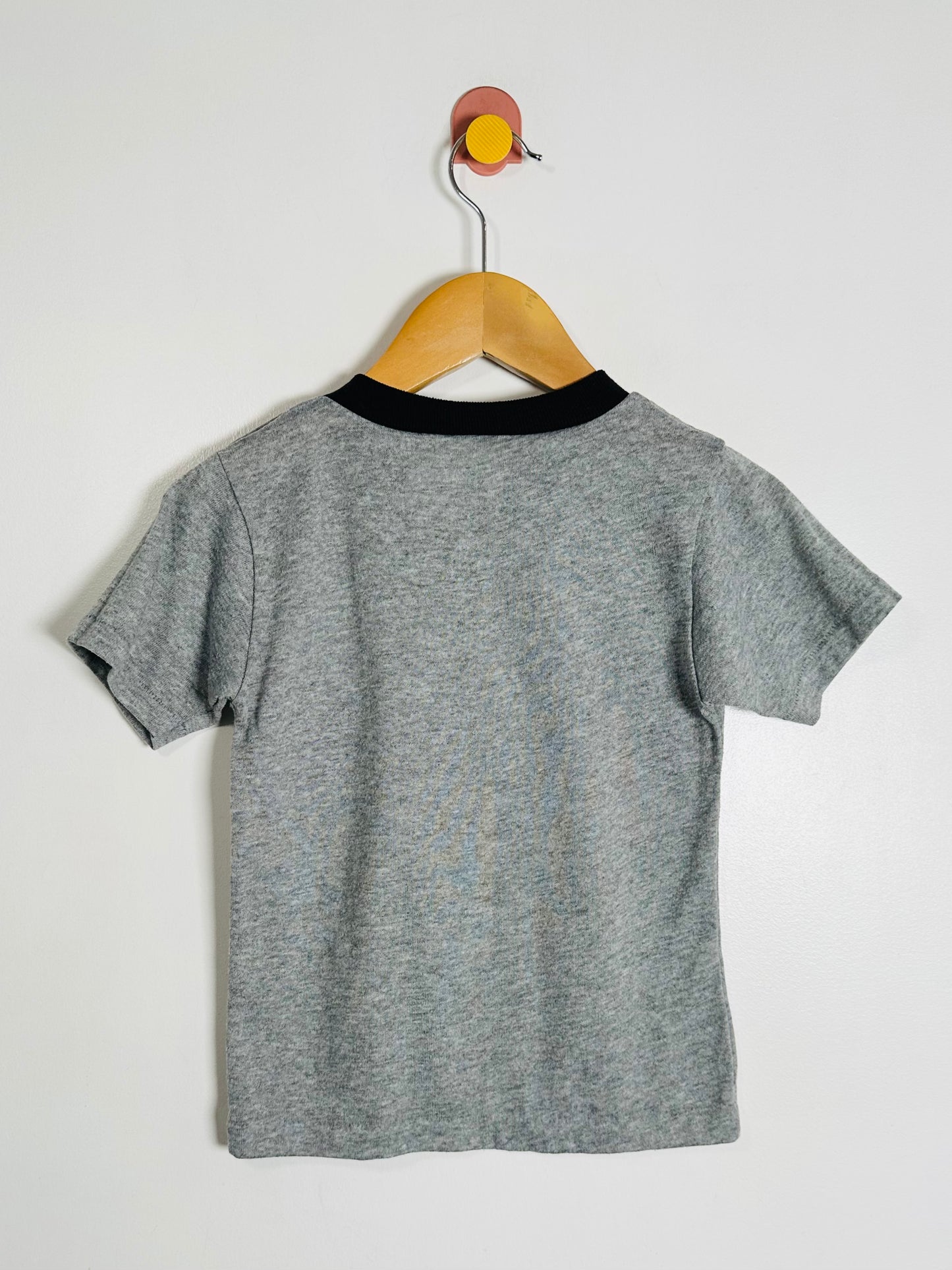 Gray t-shirt with black collar on a wooden hanger against a white background