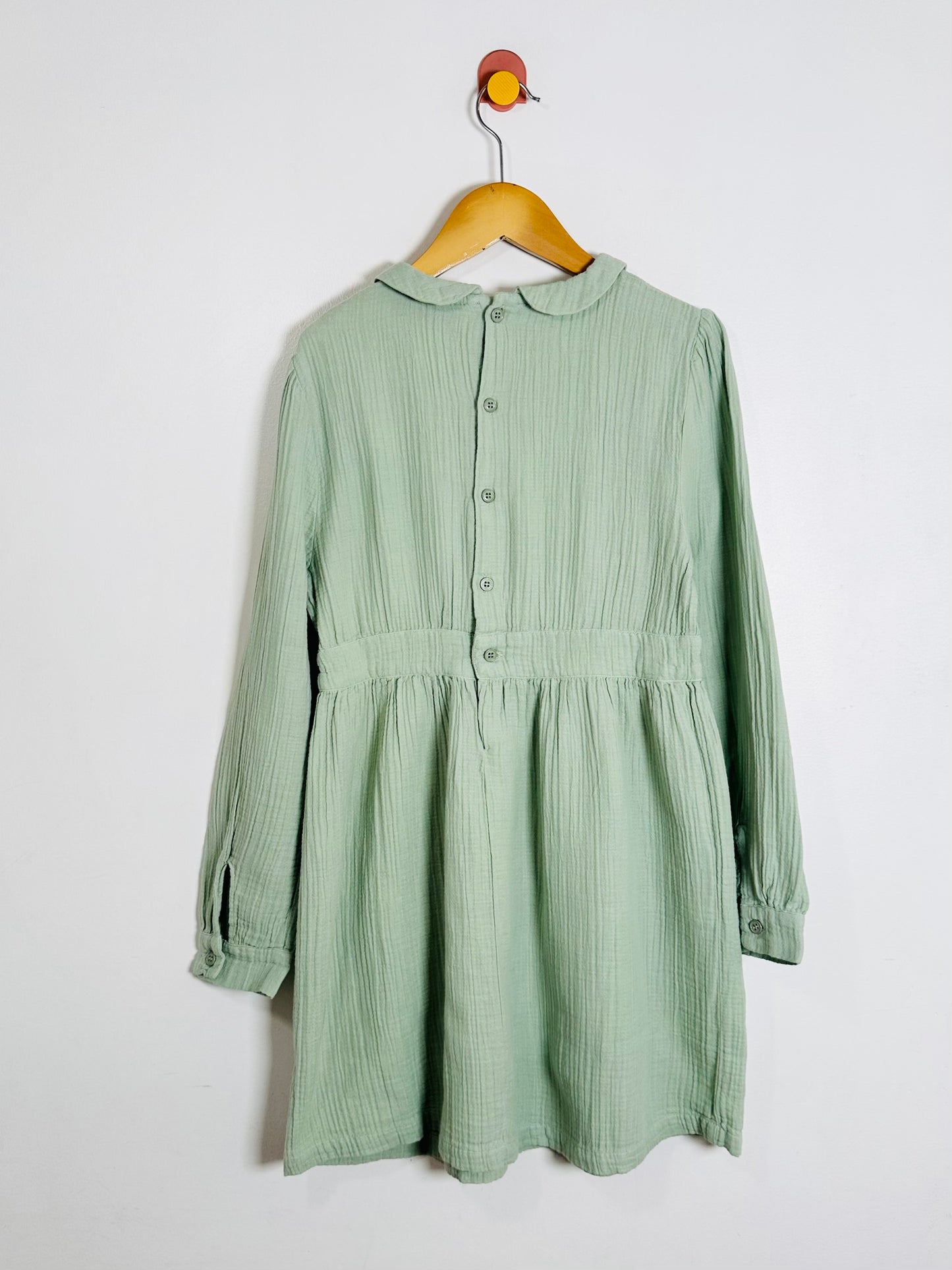 Green dress on a hanger against a white background