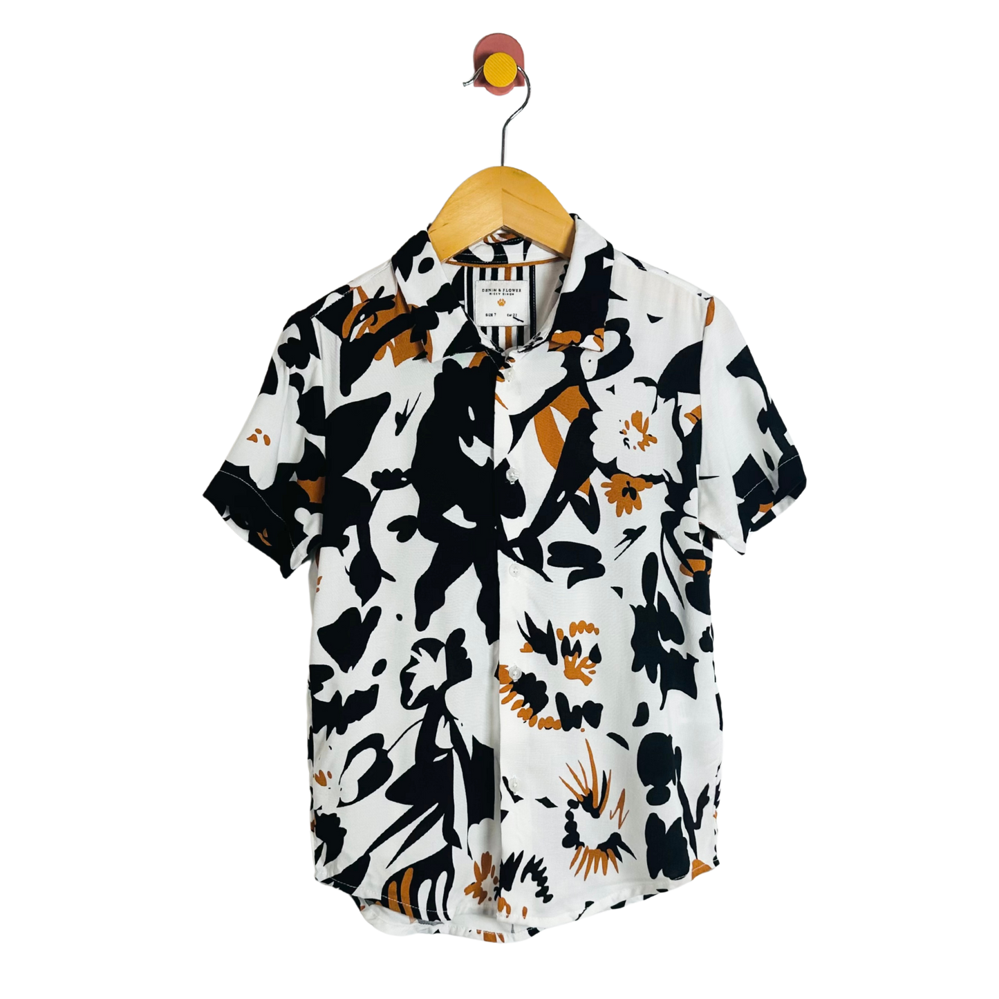 Short-sleeve shirt with black and orange abstract pattern on a hanger against a white background