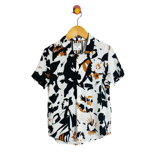 Short-sleeve shirt with black and orange abstract pattern on a hanger against a white background