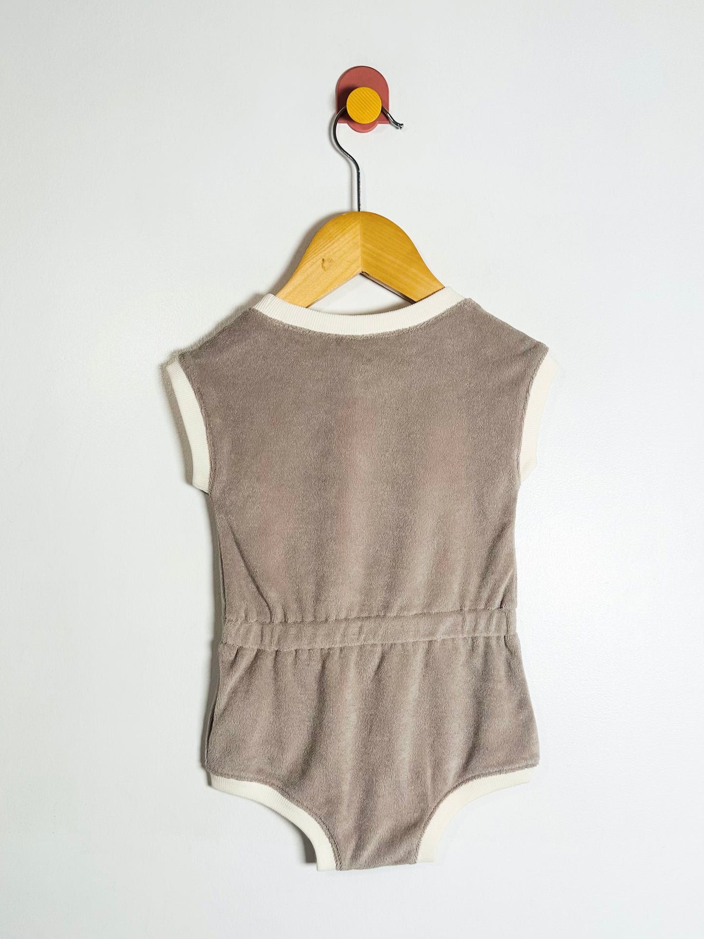 Brown baby romper on a wooden hanger against a white background