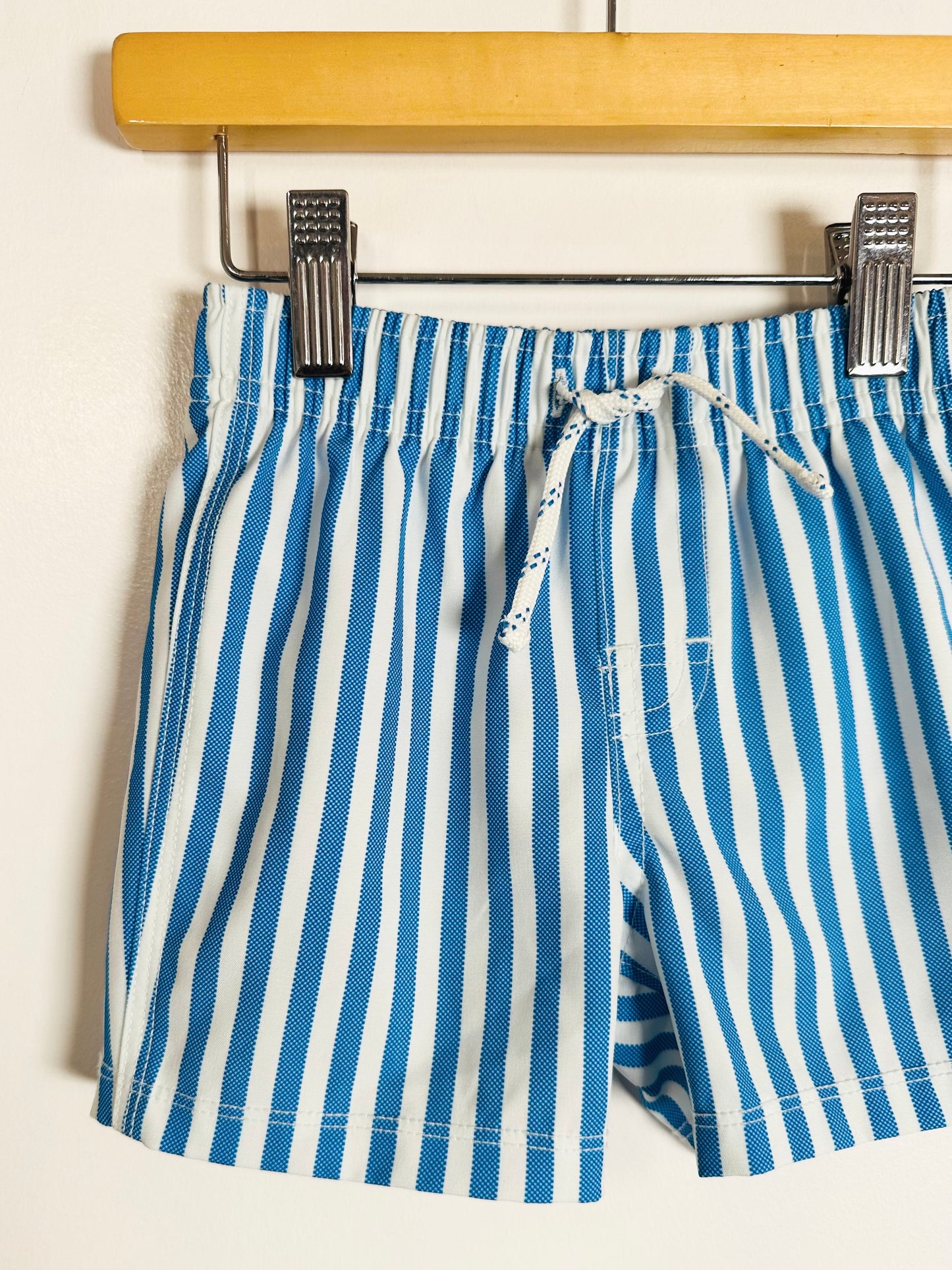 Blue and white striped shorts on a hanger against a white background