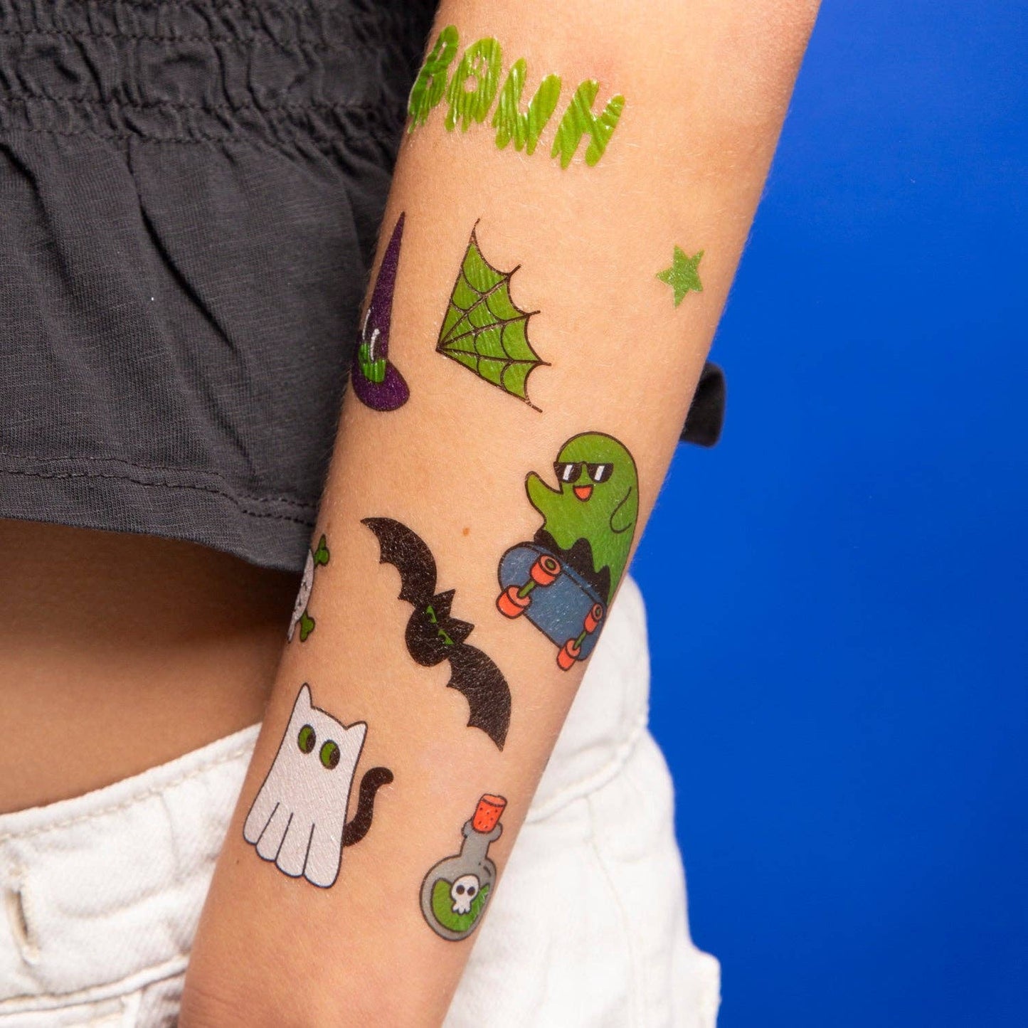 Halloween-themed temporary tattoos on a person's arm with a blue background.