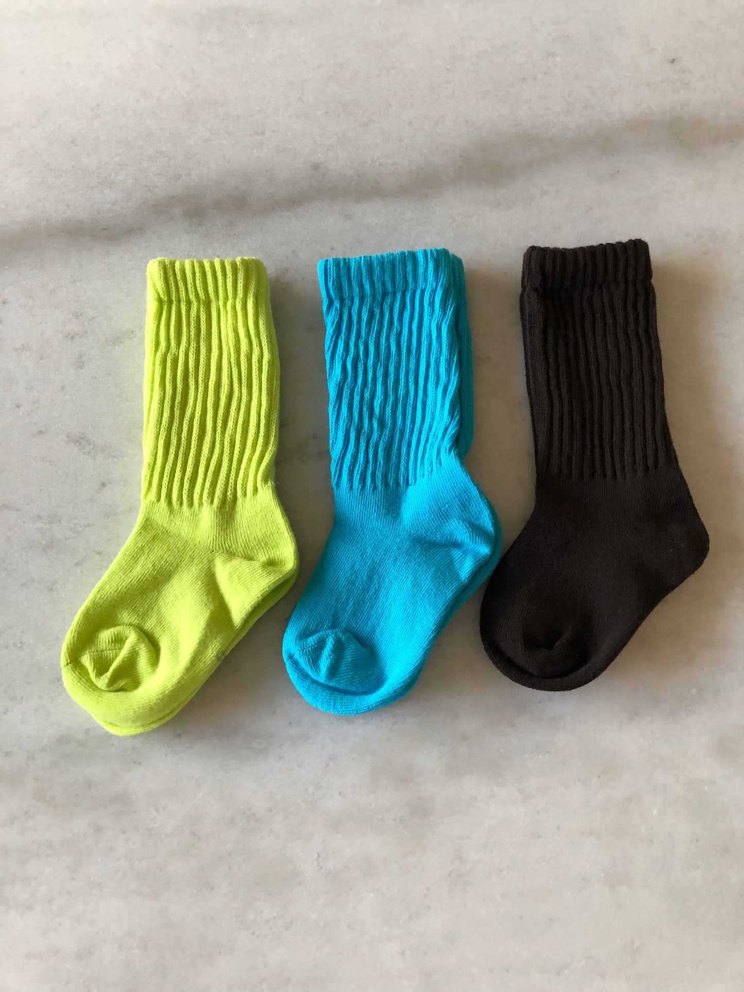Three socks in yellow, blue, and black on a light gray surface
