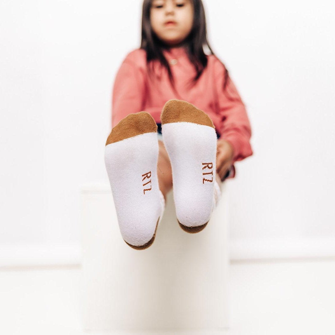 Child wearing white socks with brown toes and heels on a white background