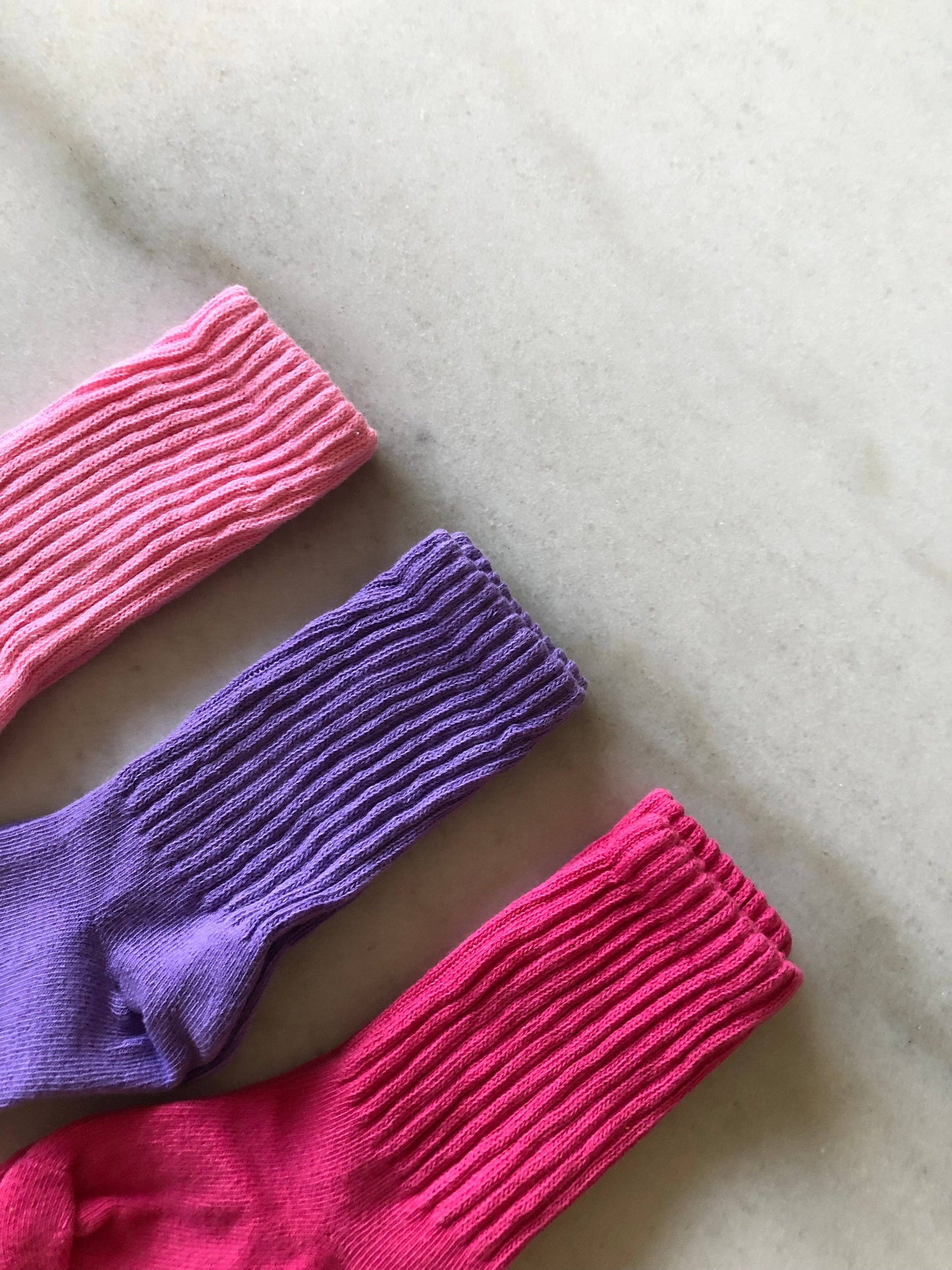 Three pairs of colorful ribbed socks on a light surface