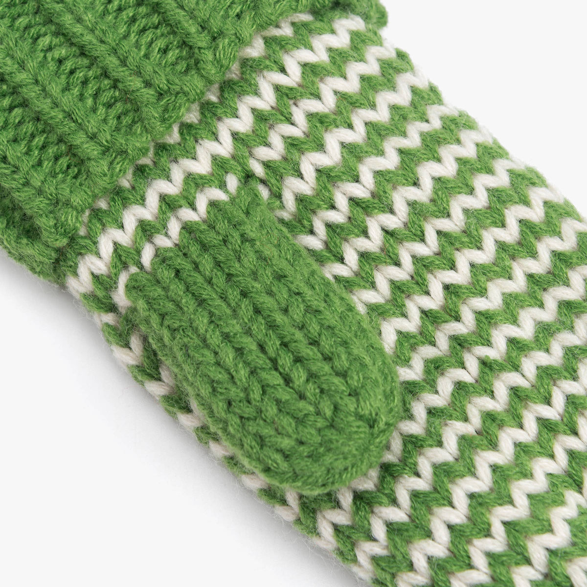 Close-up of a green and white knit accessory, showing a ribbed cuff, a looped finger pocket, and a zigzag striped pattern on a white background.