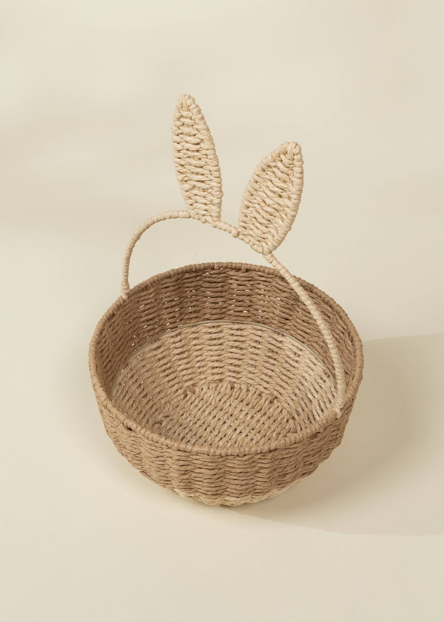Woven basket with bunny ears on a beige background