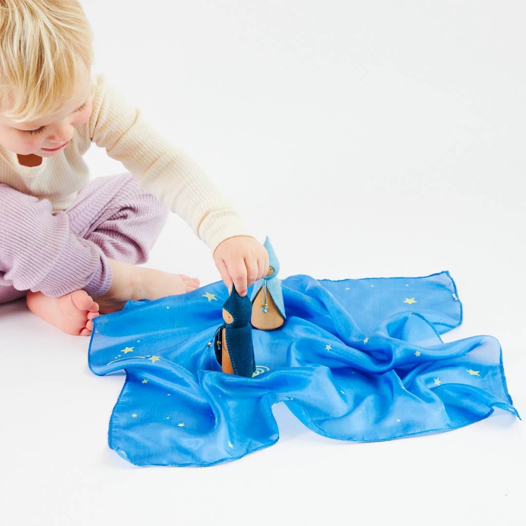 Child playing with a blue scarf on a white background