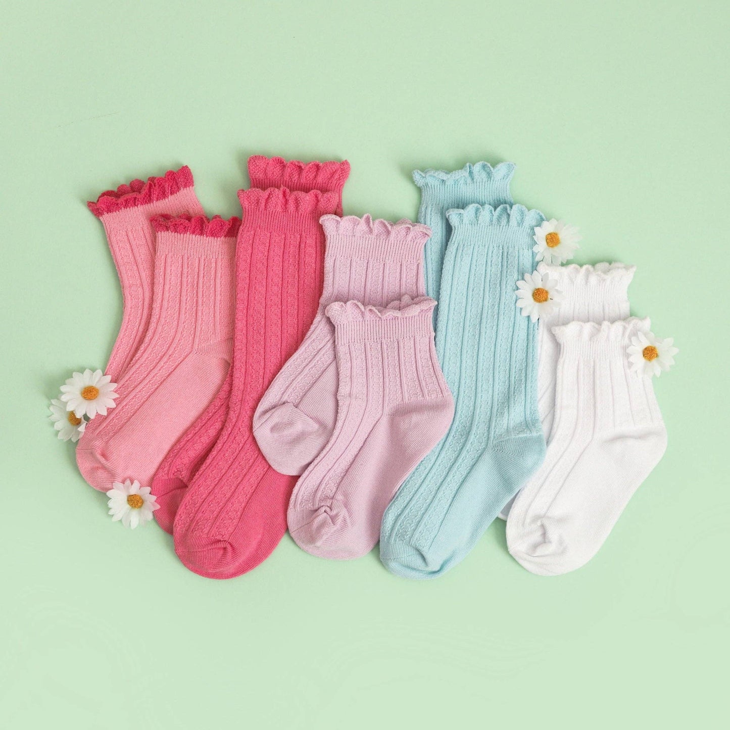 Set of colorful socks with ruffled edges on a light green background