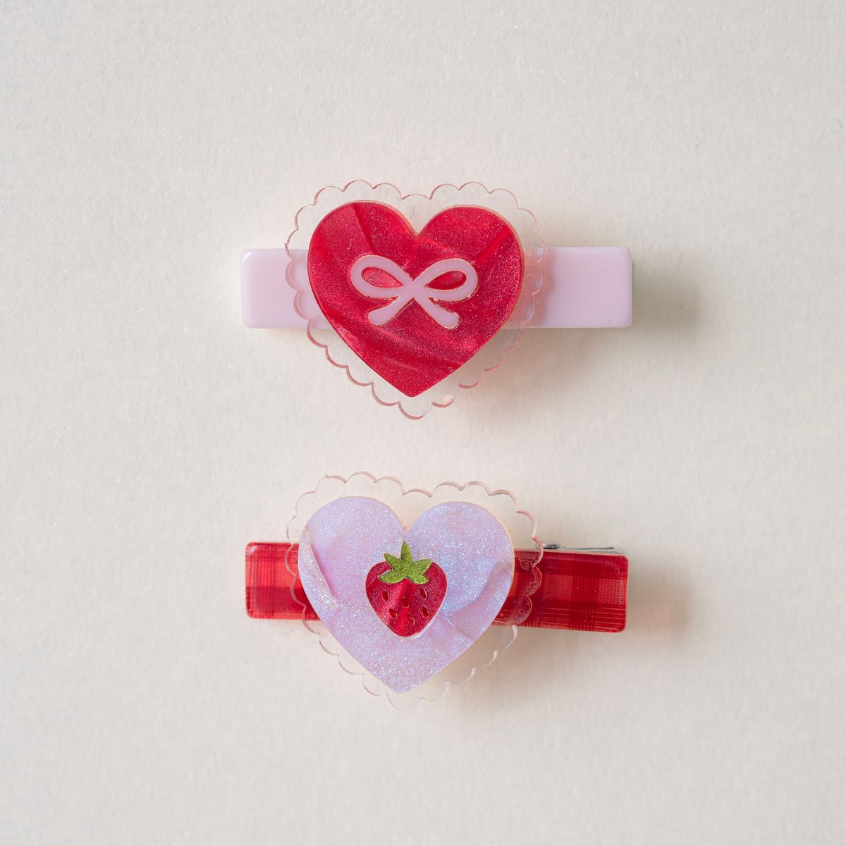 Two heart-shaped hair clips with decorative elements on a light background