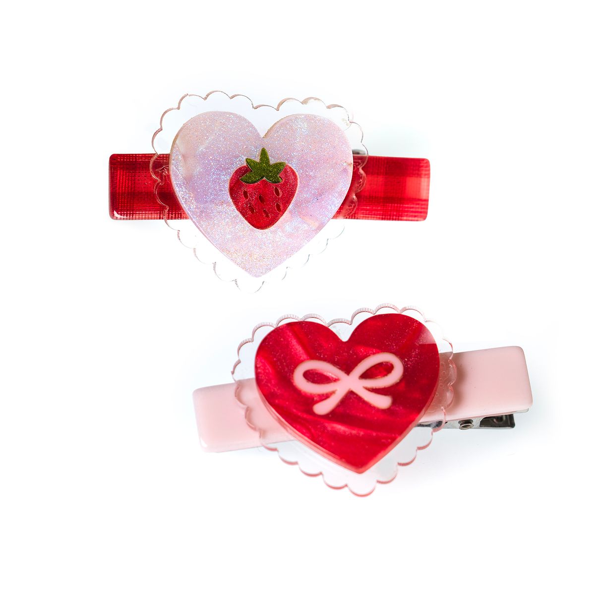 Two heart-shaped hair clips with strawberry and bow designs on a white background