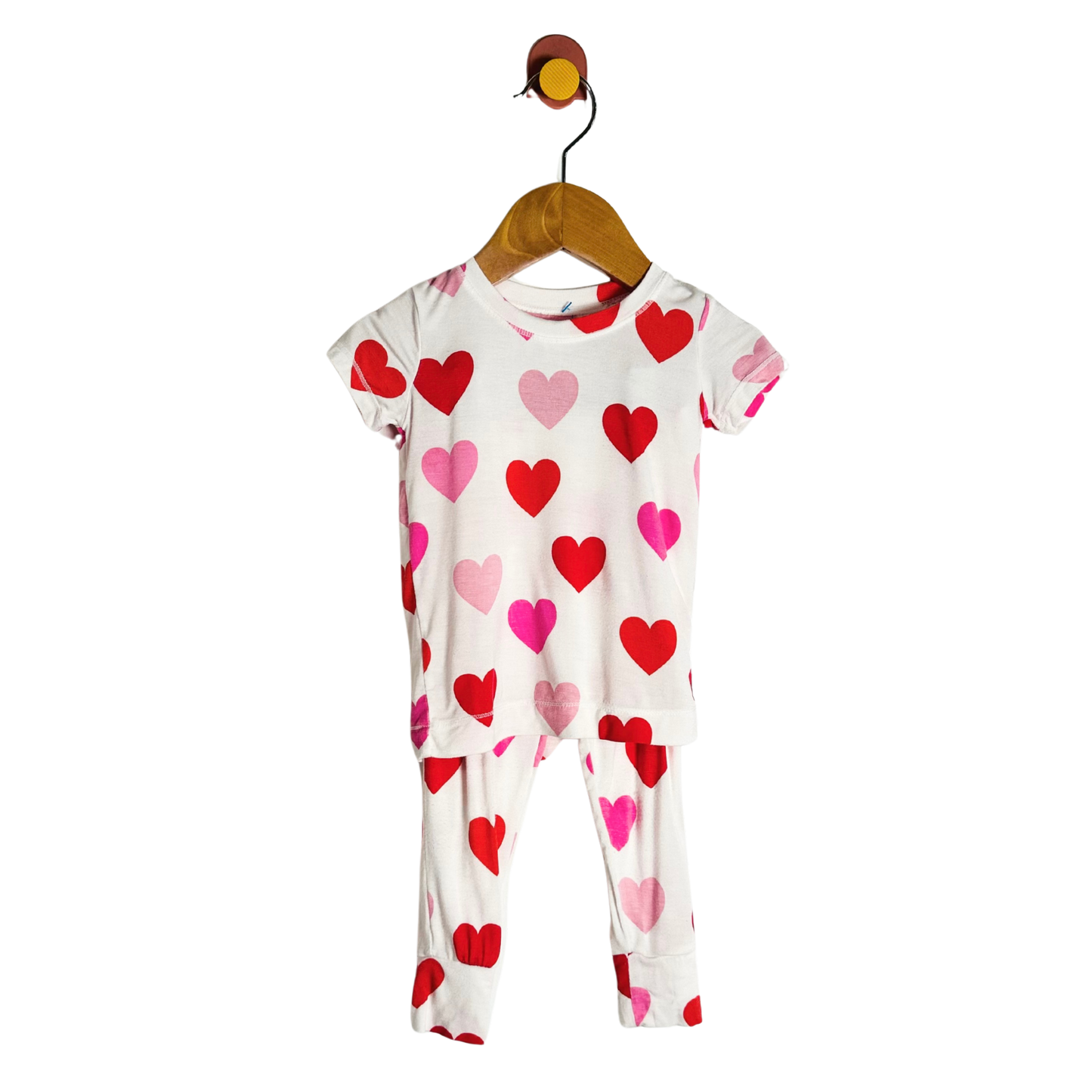 Children's pajama set with heart pattern on a hanger against a white background