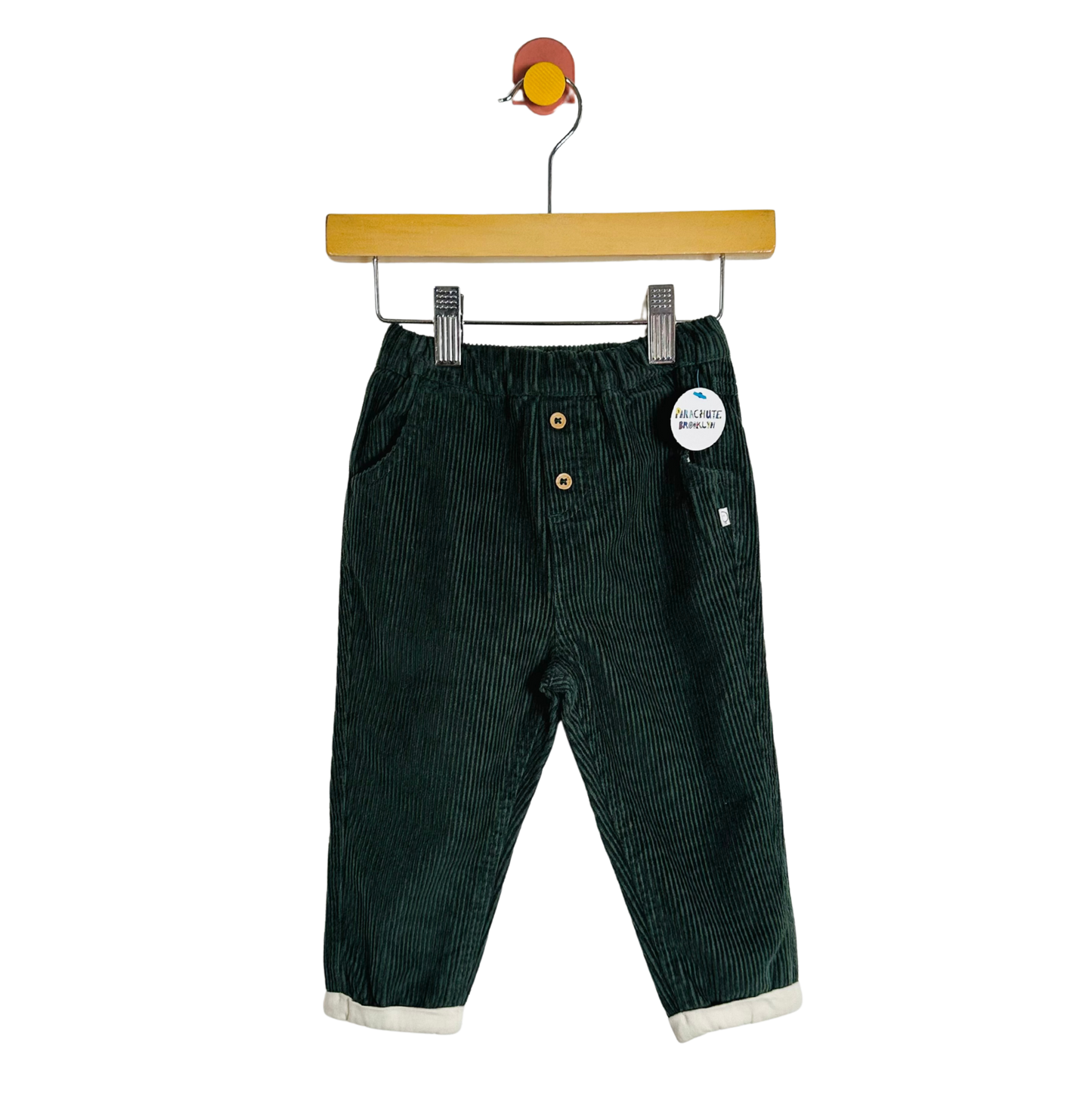 Green corduroy pants on a hanger with a white background