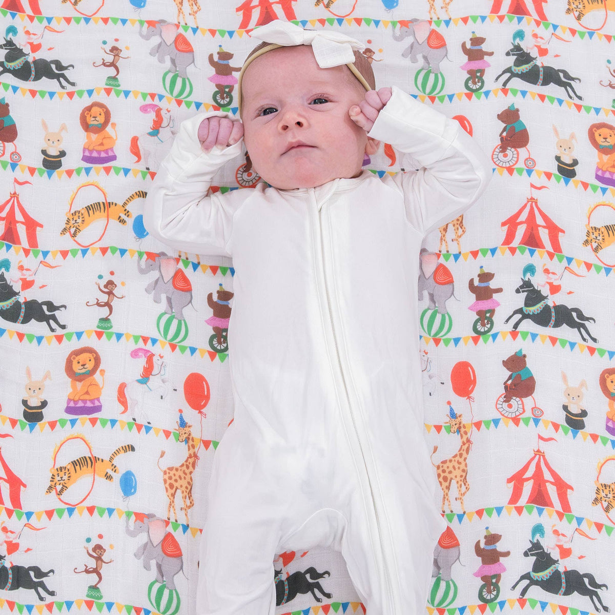 Baby lying on a colorful patterned blanket with animal illustrations