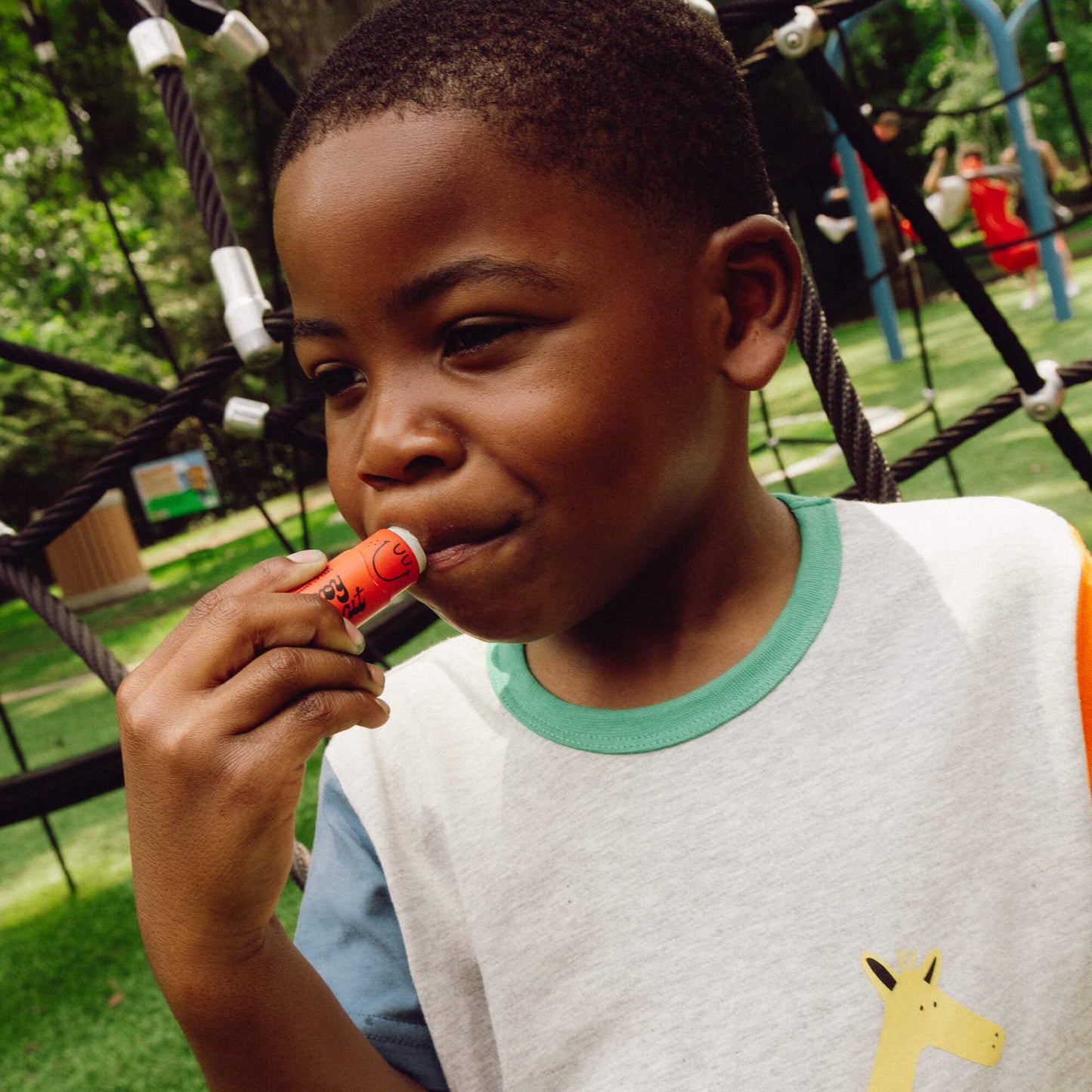 Child applying lip balm in a playground setting