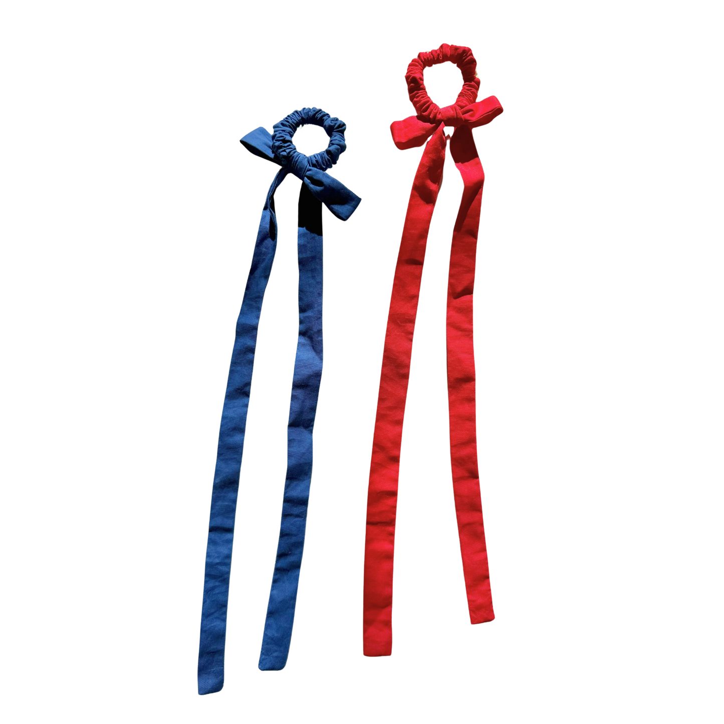 Two fabric hair bows with long ribbon tails, one in blue and one in red, shown on a plain white background.