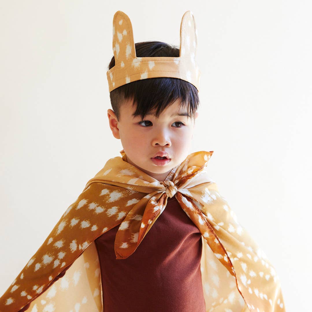 Child wearing a deer costume with a headband and cape on a white background