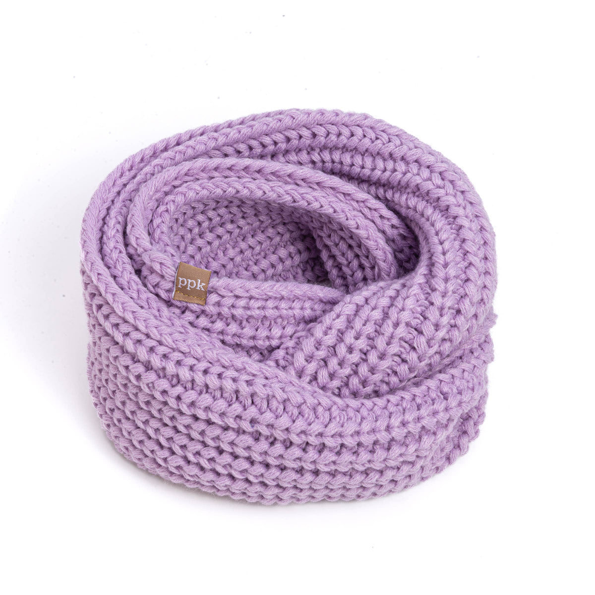 A chunky knit infinity scarf in a light lavender purple color, coiled and folded with a small brown brand tag that reads 'ppk' on a white background.