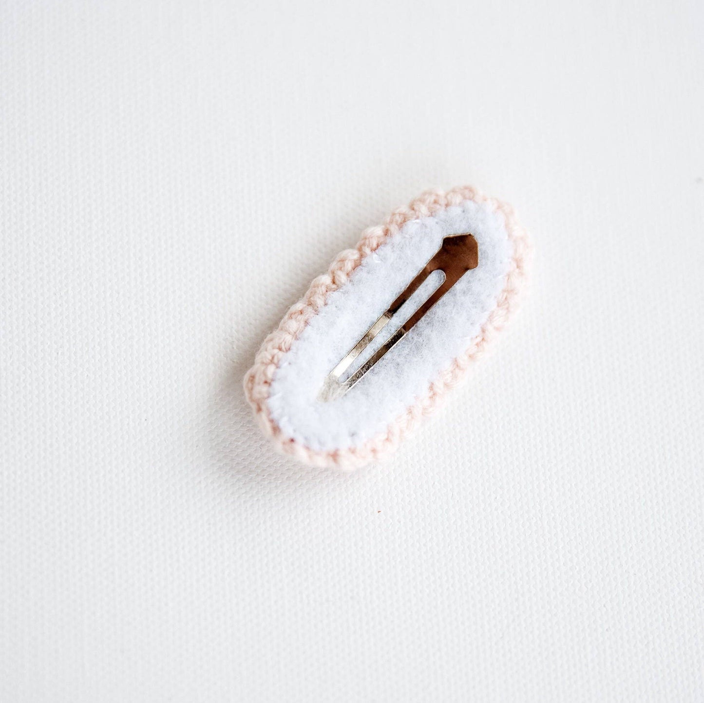 Hair clip with a white cushion and pink border on a light gray background